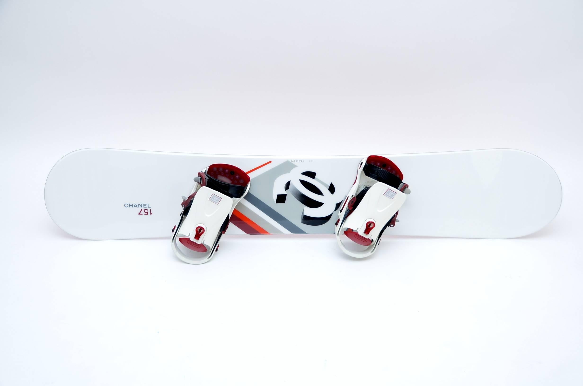 Very rare to find in this new condition Chanel snowboard with white  front and  graphic design feature  at center with iconic Chanel logo. Red underside features Chanel logo. Quilted travel case and red/white bindings included; both feature Chanel
