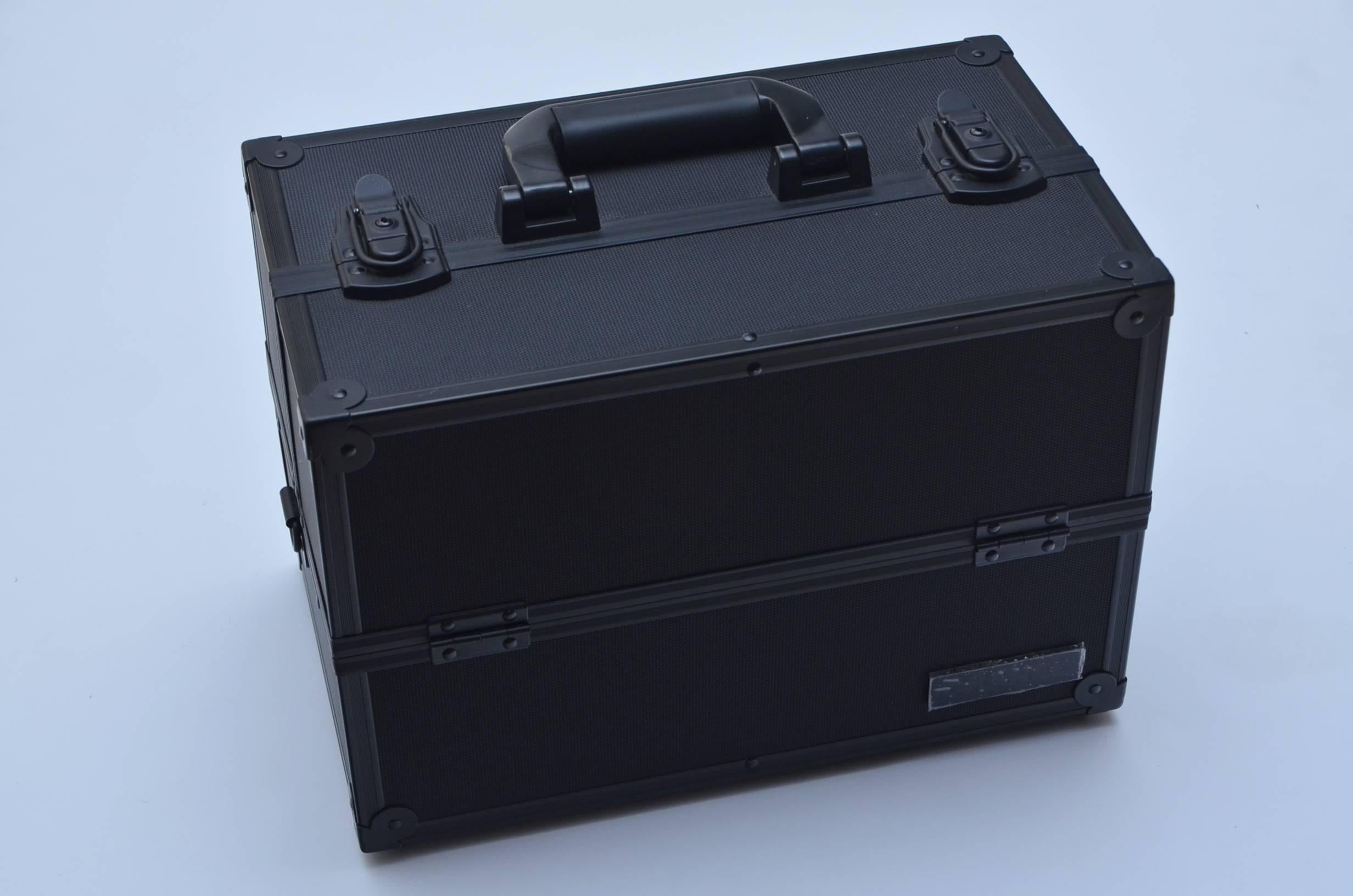 Black Chanel aluminum cosmetic case with tonal metal and resin hardware, logo placard at front, top handle, expandable interior trays with five compartments, leather trim, logo mirrors and latch closure. 
Includes three slotted inserts some covered