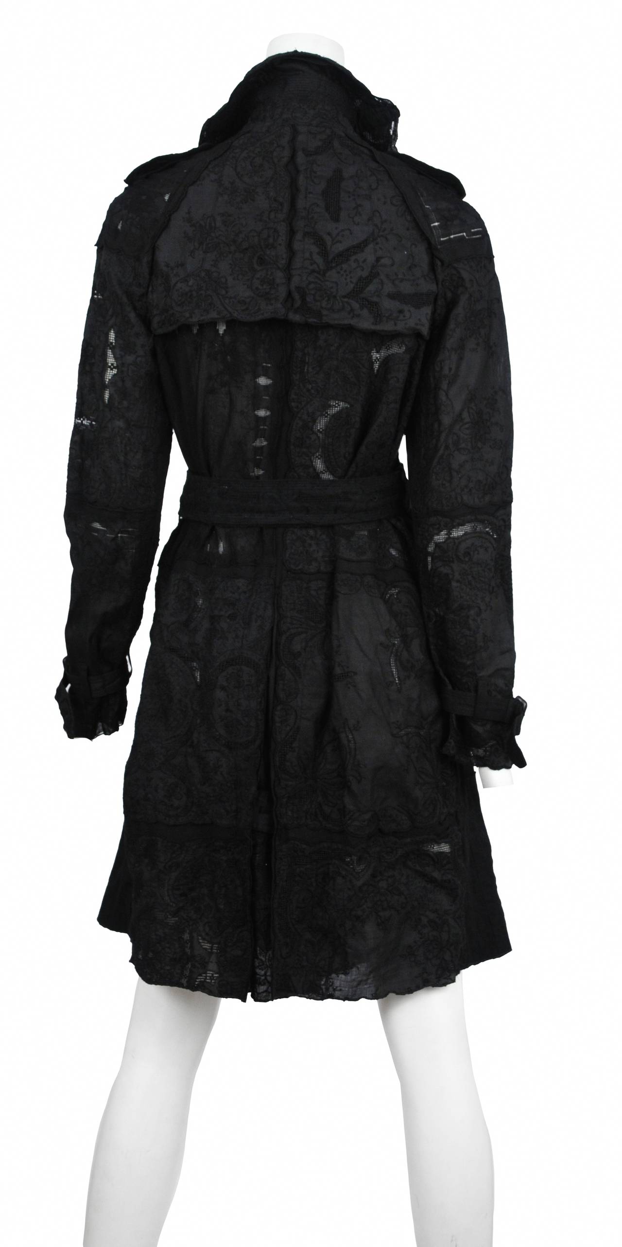Vintage Comme des Garcons black embroidered trench coat with epaulets at shoulders, flap pockets at sides, vent at back, belt at waist and front double-breasted button closures.