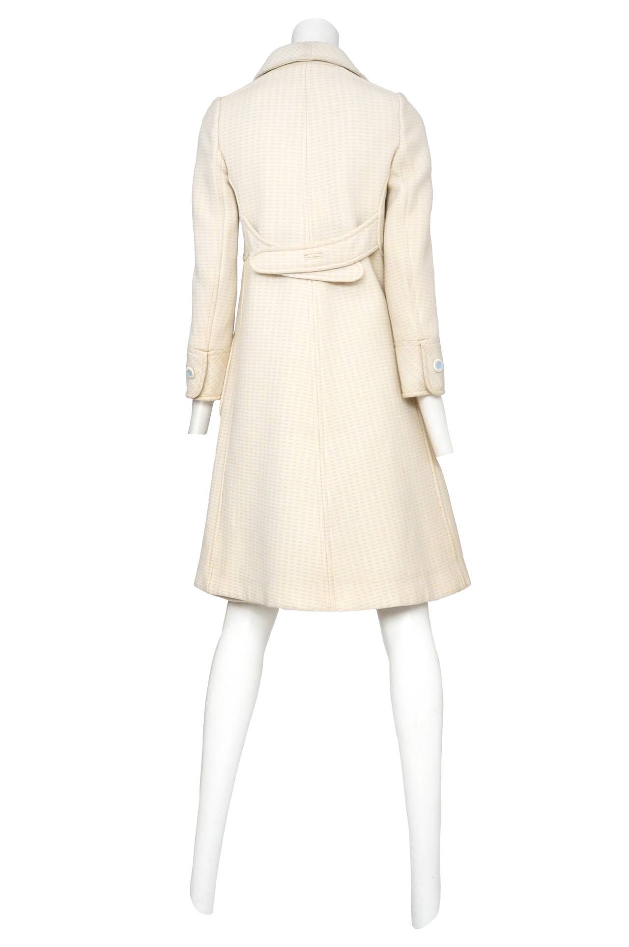 Vintage Andre Courreges cream wool coat with baby blue stitching through out fabric. The coat features an exaggerated collar and white buttons with baby blue centers and two large side patch pockets. The ensemble comes with a matching a-line