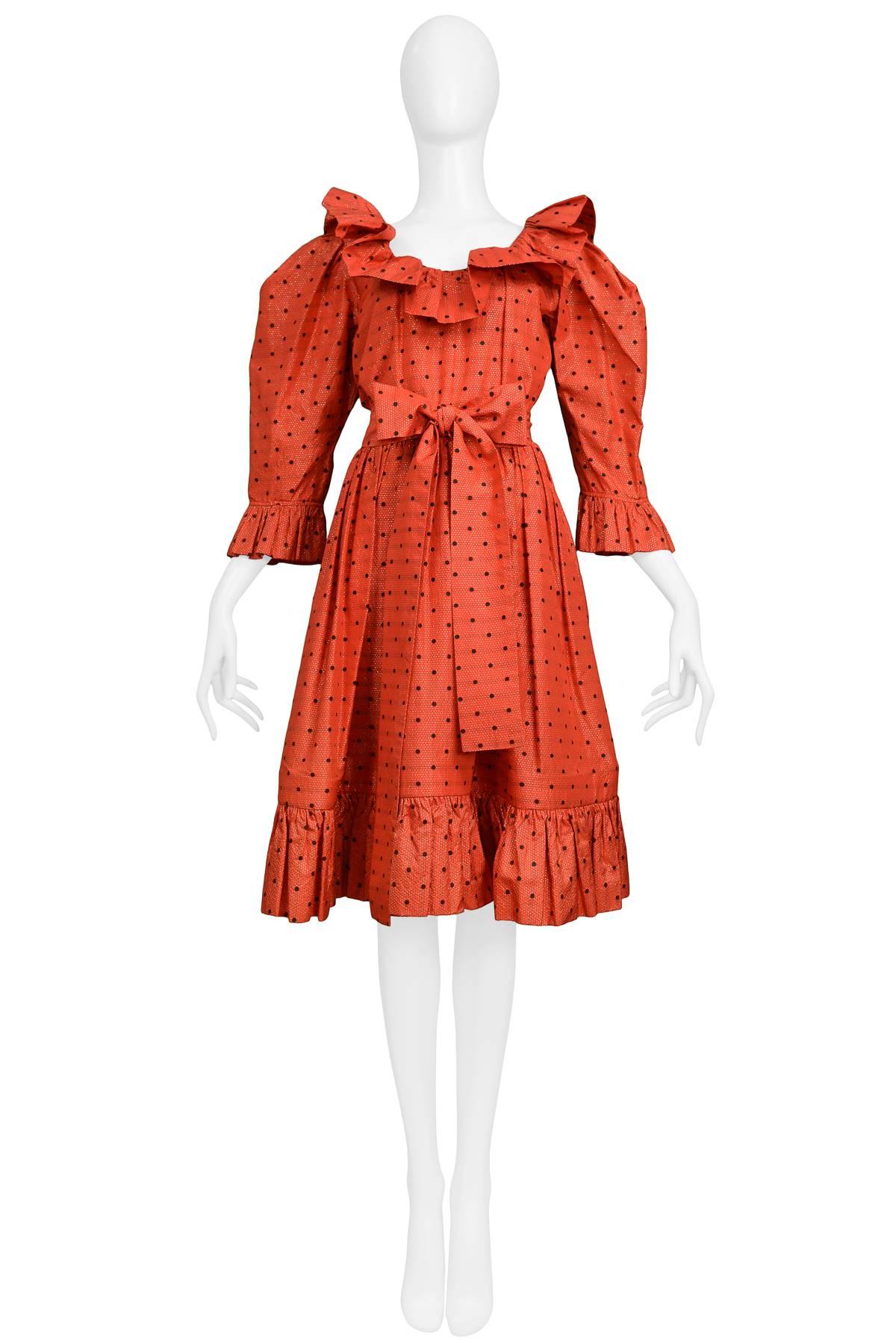 Vintage Yves Saint Laurent red taffeta evening frock featuring black polka dots and gold thread through out. The dress is adorned with ruffles at the neckline, cuffs and flounce and features a gathered waist with a matching sash.
Please inquire for
