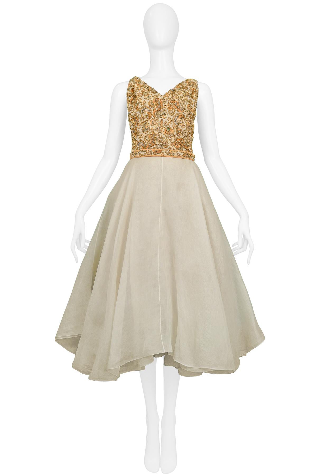 Vintage James Galanos for Amelia Gray of Beverly Hills sleeveless cocktail dress featuring a gold-tone beaded paisley bodice and off-white organza circle skirt. Circa 1960s.

Excellent Condition.

Size: 2/4