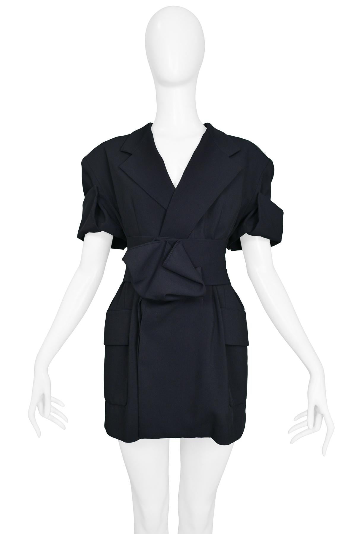 Vintage Yohji Yamamoto navy short sleeve blazer tunic featuring a wide lapel, side pockets, matching waist belt at front, and origami style pleating at the cuffs and belt center.

Excellent Condition.

Size: Small