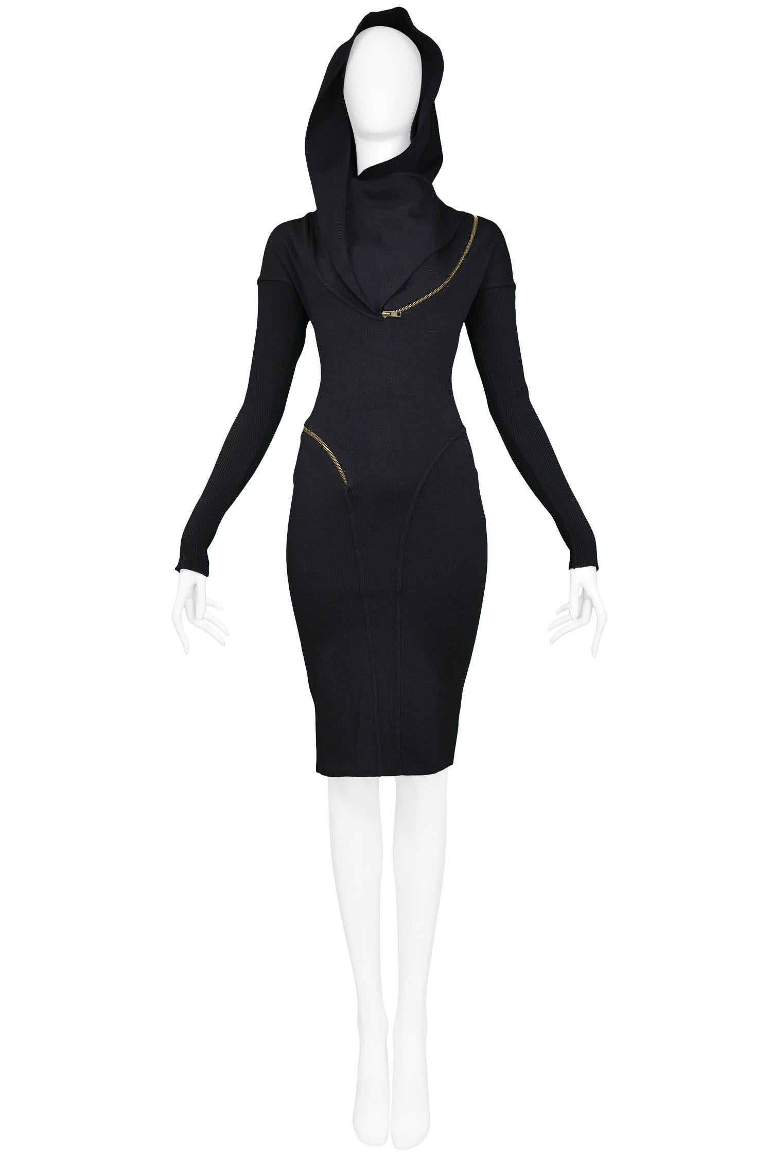 Vintage iconic museum quality 1986 Azzedine Alaia black knit hooded zipper dress featuring a slim body-con fit, long sleeves & brass zipper detail that wraps around the body. The collar can be zipped into a hood or worn unzipped as a collar.
