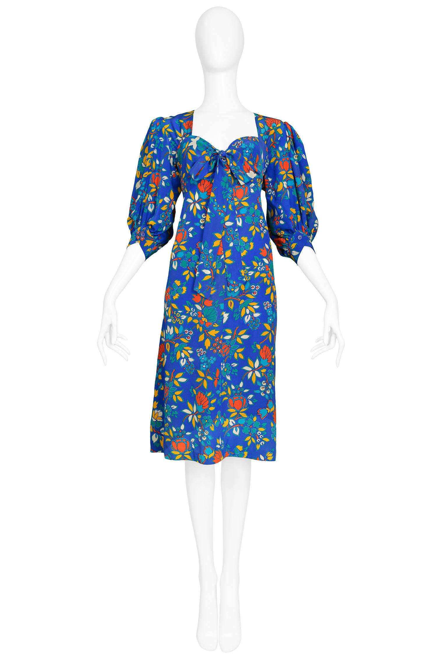 Vintage Yves Saint Laurent blue dress with multi color floral print. The dress features a sweetheart neckline, long sleeves that gather at the shoulder and button at the wrist & fabric that ties into a bow at the bust. 

Excellent Condition.

Size: