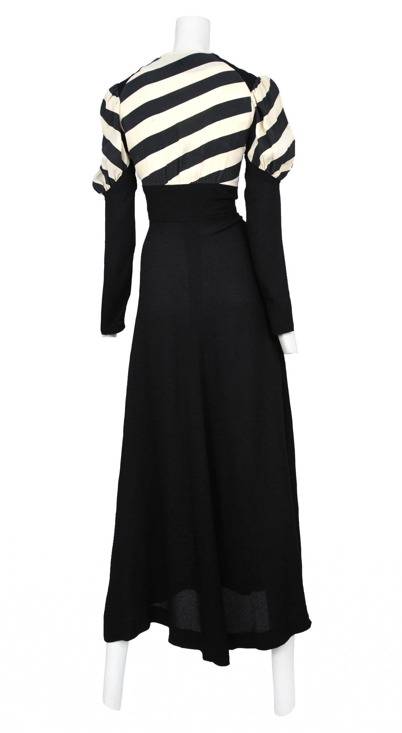 Vintage Ossie Clark moss crepe button front maxi dress featuring a black and white stripe print on the upper bodice and upper sleeve. The striped crepe is sewn into a deep v neckline and is attached to an empire black crepe button front skirt with