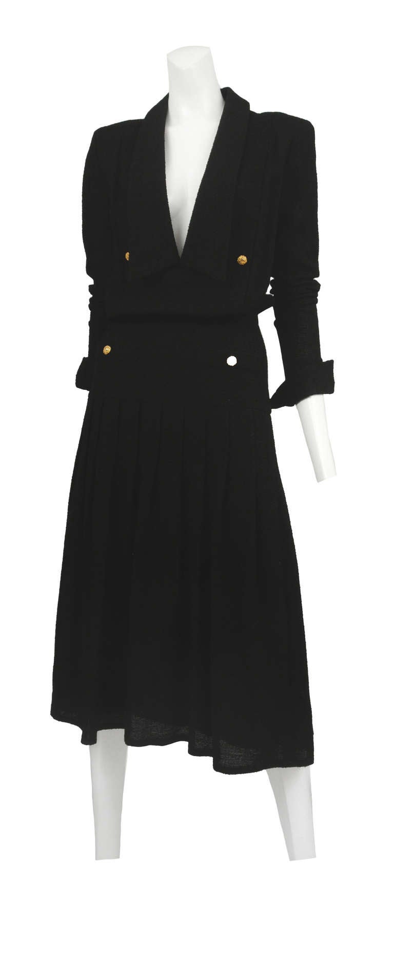 Black silk linen pleated dress with plunging collared neckline and iconic gold button detail.