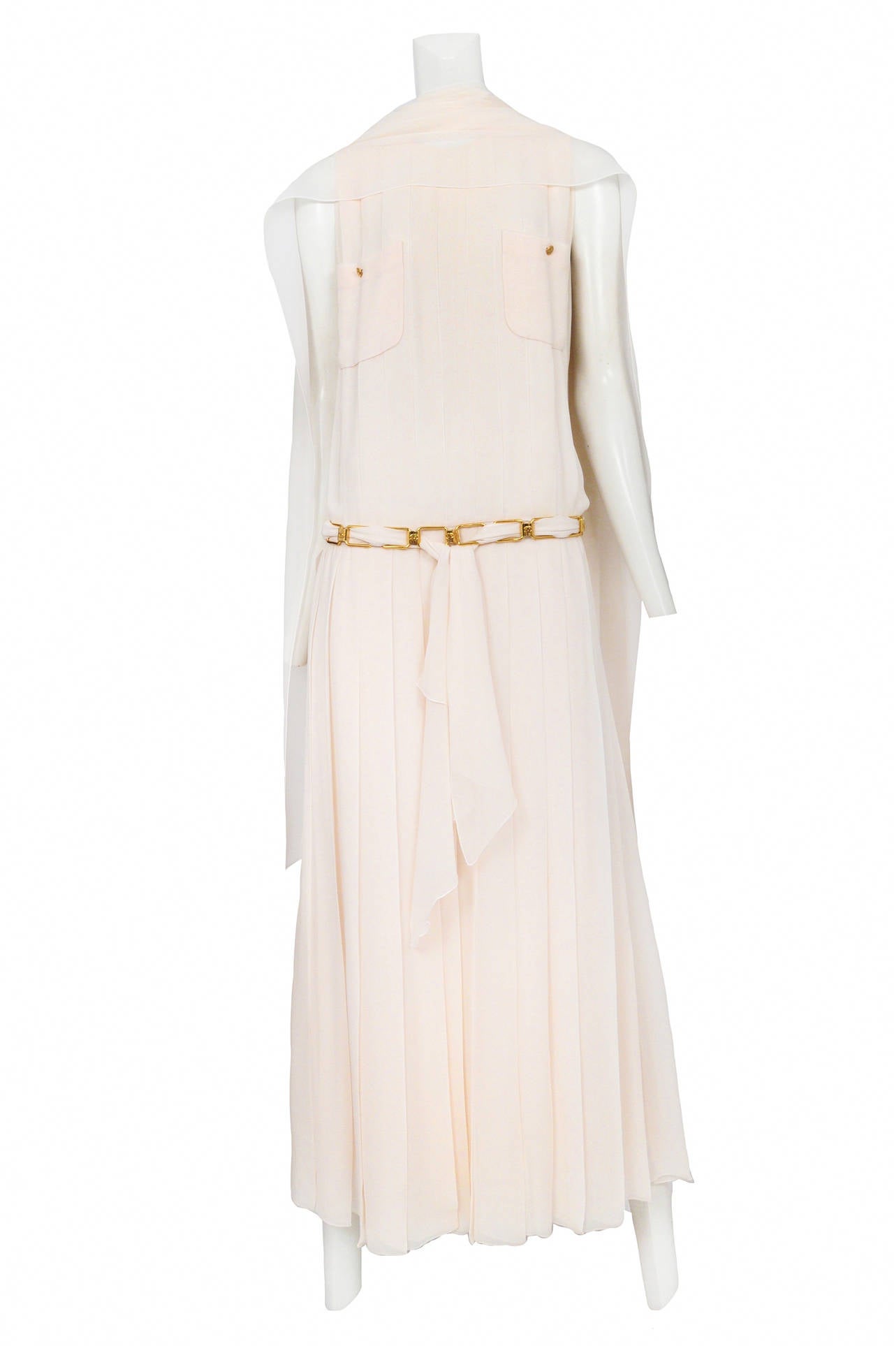 Vintage Chanel 1920's style ivory button back drop waist dress featuring pleating throughout, two pockets at chest adorned with gold buttons and a gold link belt threaded with matching ivory chiffon that sits low on waist. The dress comes with a