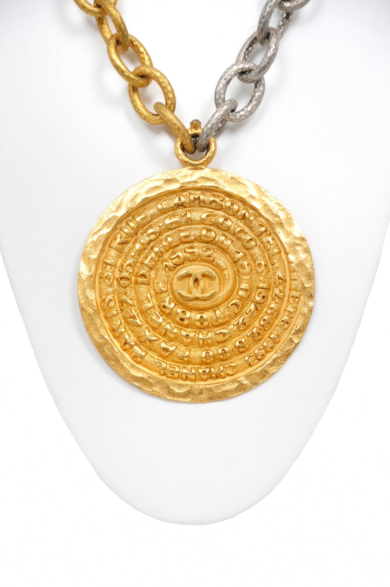 Vintage Chanel dial necklace featuring a large gold tone dial pendant labeled with Chanel's Paris address hanging on a two tone oversize chain.
