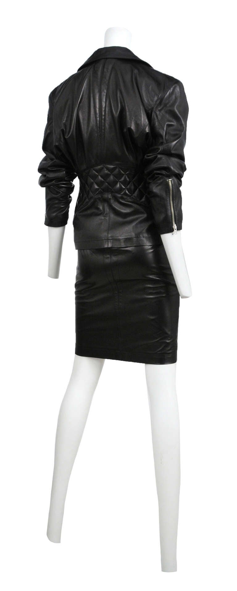 Azzedine Alaia black classic leather motorcycle suit in black lambskin with silver hardware. HIgh waisted pencil skirt with zipper detail paired with a fitted waist jacket with quilted detail at back.