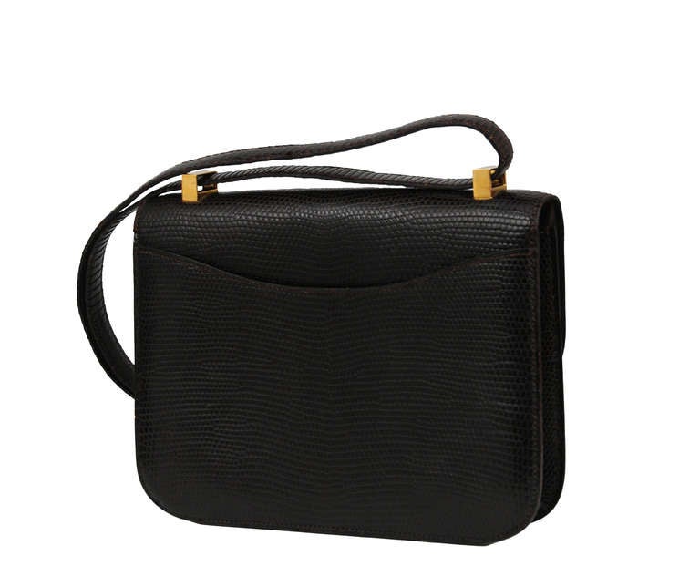 Hermes 23 cm Constance bag in deep chocolate brown lizard skin with gold hardware.