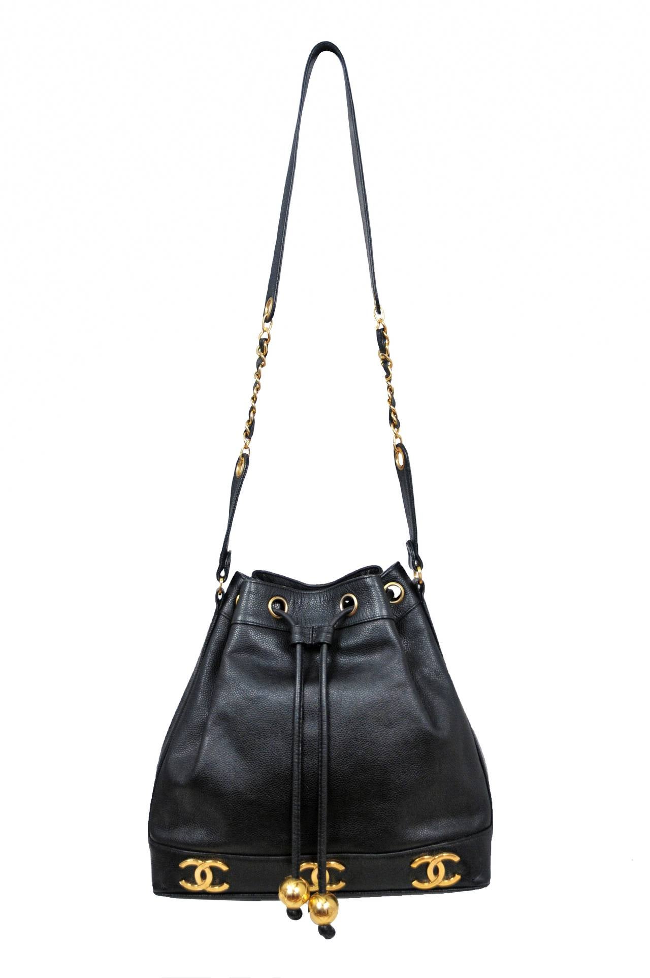 Vintage Chanel caviar black leather bucket bag with gold CC logo's surrounding the base. Drawstring closure embellished with gold globe hardware.

Strap length 21