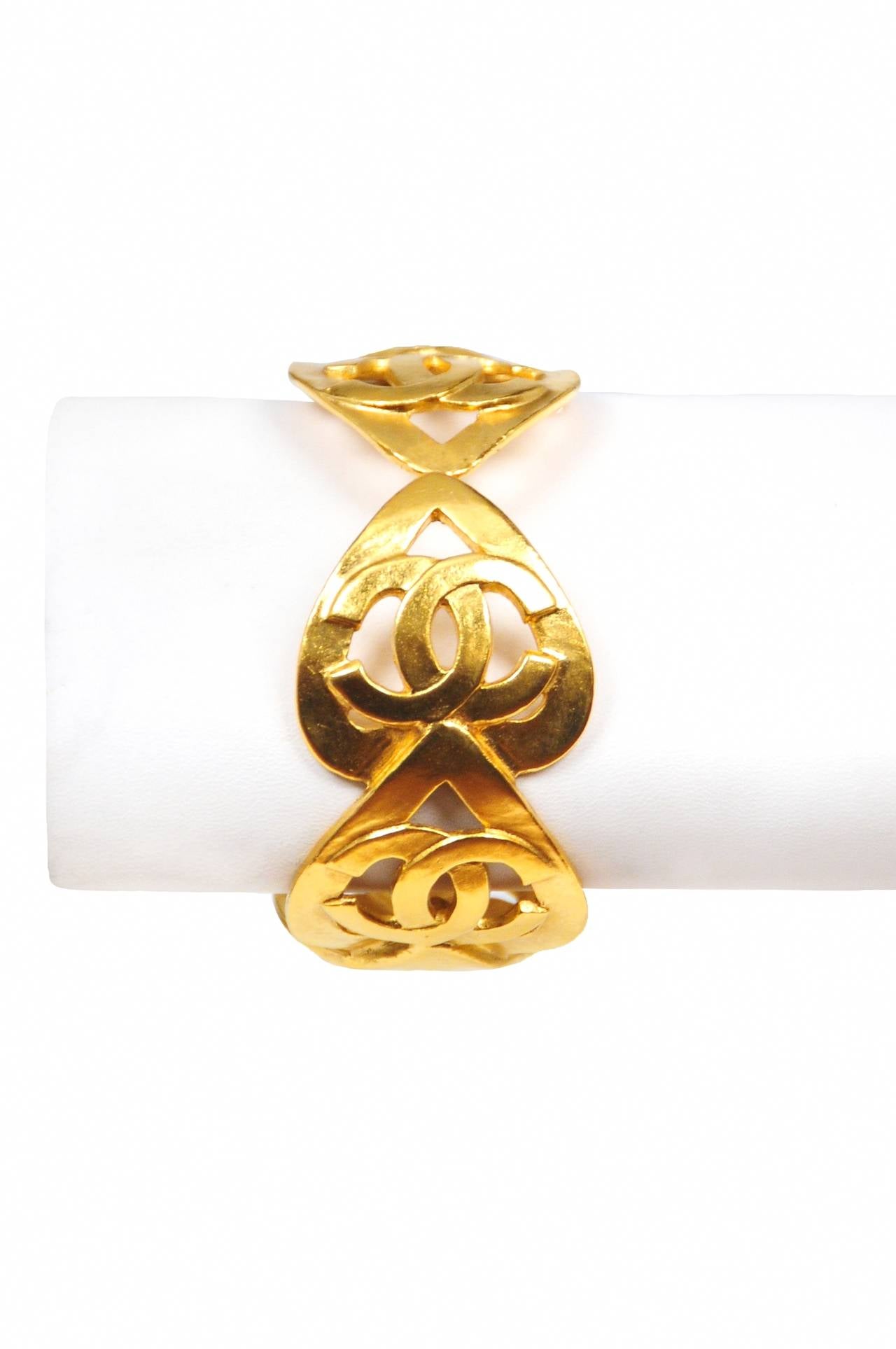 Vintage Chanel gold tone cuff featuring iconic interlocking CC's atop interlocking hearts.