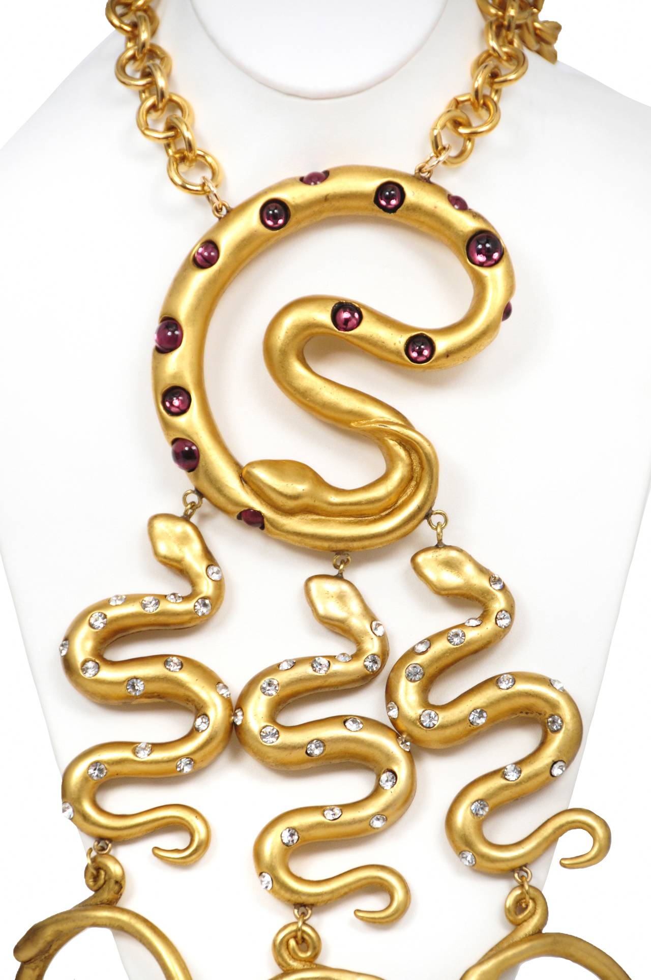 Vintage Escada serpent motif necklace featuring three jewel encrusted gold tone snakes that hang from a large purple jewel encrusted coiled snake that sits perched at the collar suspended by a gold tone link chain.