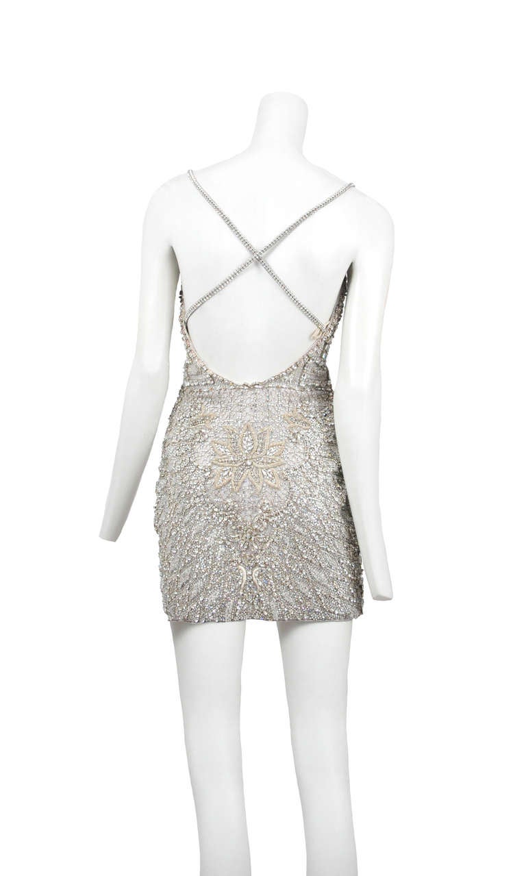 A rare Gianni Versace couture cocktail dress from the 1990's. 
The dress is made of a white gauze ground and is entirely covered with multi- shape crystal rhinestones, raised silver purl embroidered leaves, ivory satin palmettes and scrolls. The