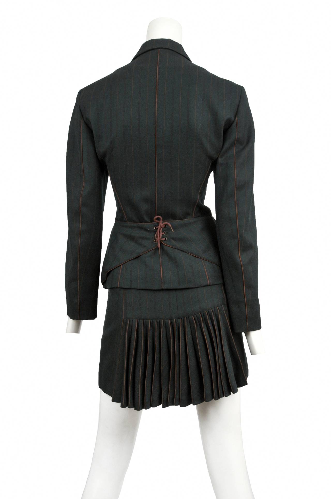 Vintage Azzedine Alaia woven rayon dark green pinstripe two piece suit. Corset seam detailing shape the curves of the waist line with a flirty accordion pleat inset at the back of the skirt.