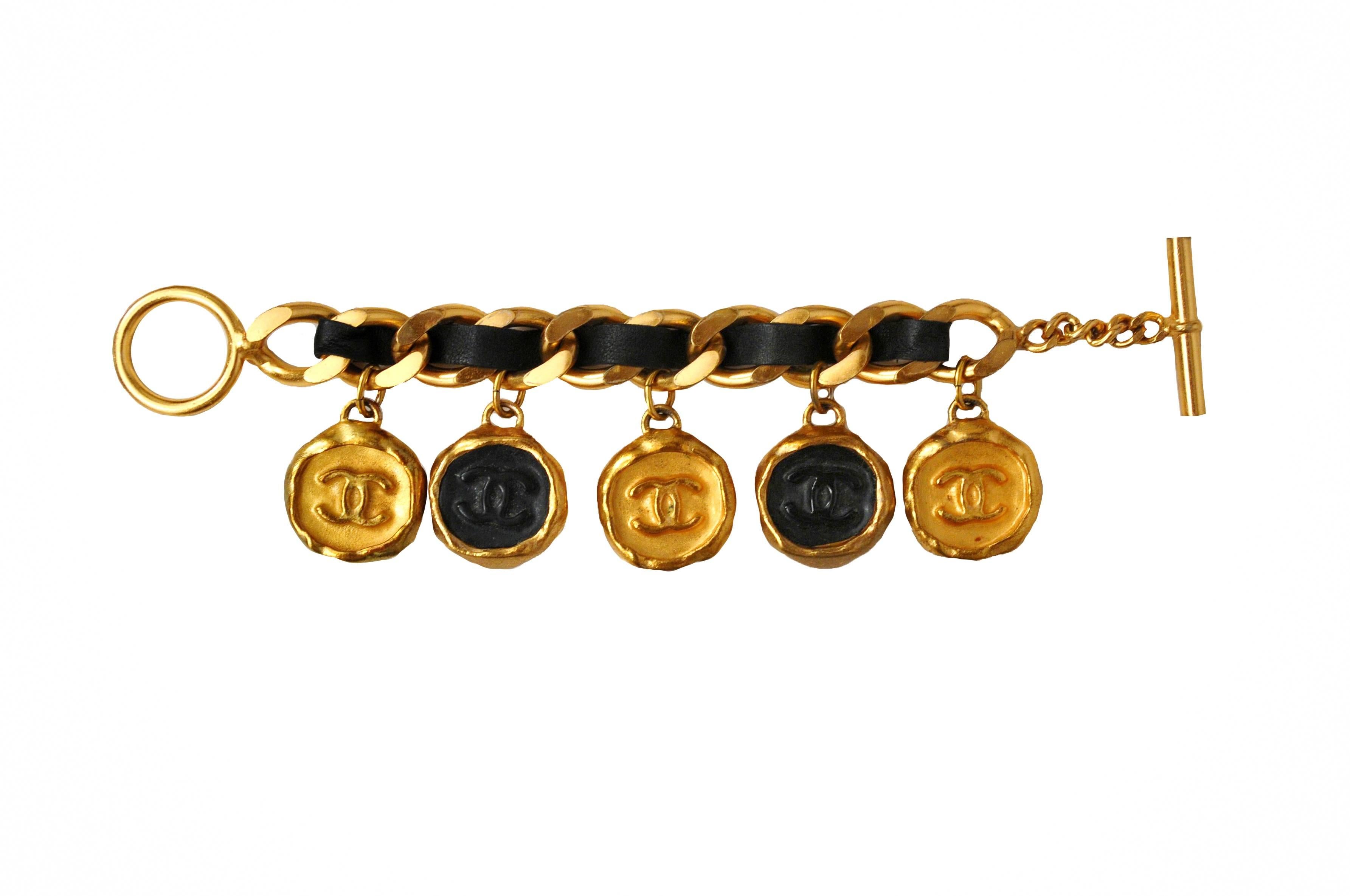 Vintage Chanel charm bracelet. Gold metal and black acrylic CC stamped charms on gold heavy chain with black leather woven throughout. Stamped Chanel on the toggle clasp. 