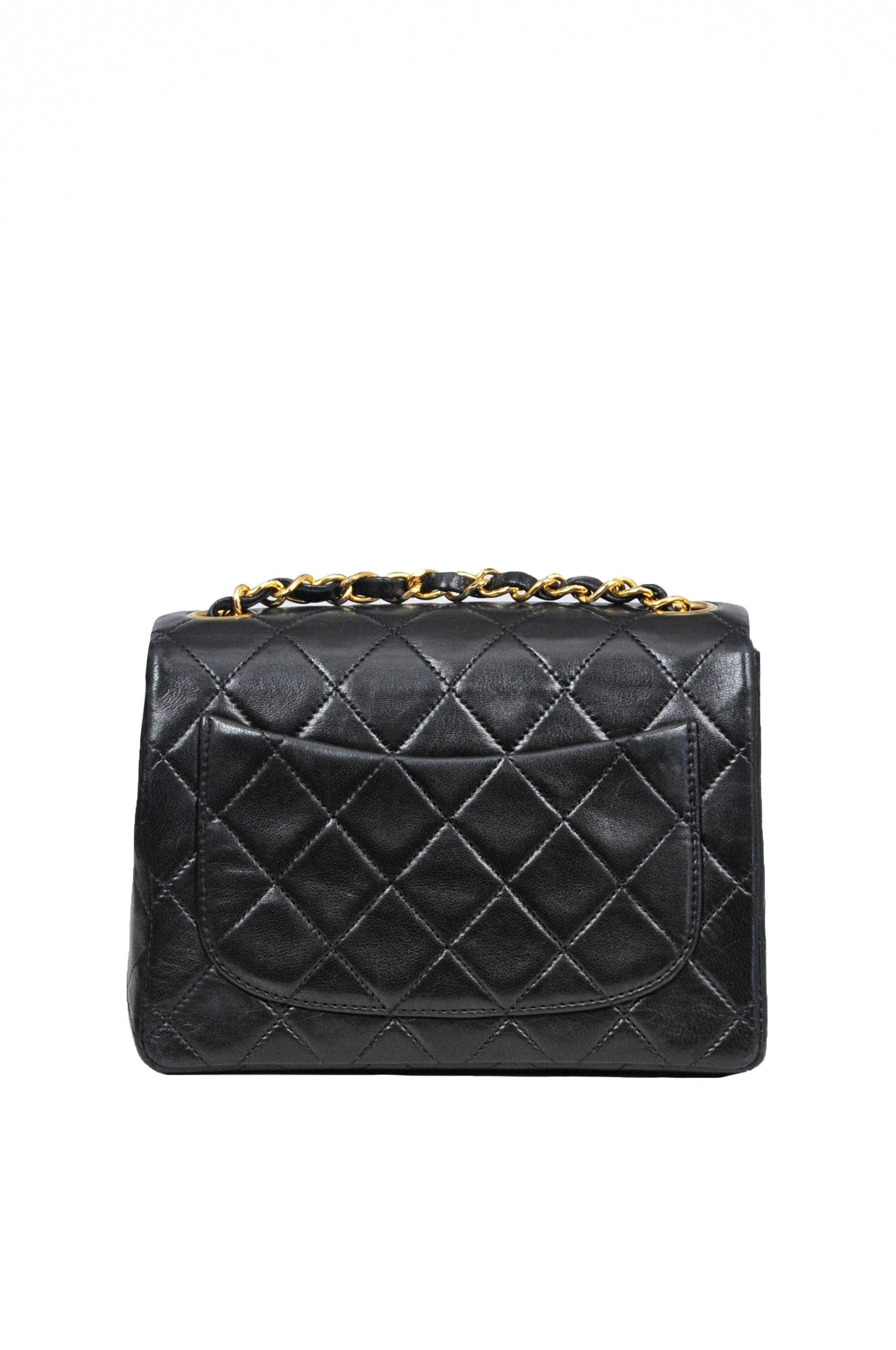 Vintage Chanel Classic mini bag in black quilted lambskin featuring burgundy leather interior lining, iconic leather and gold tone chain woven straps, a classic patch pocket at the back, one inner pocket, one inner hidden zip pocket, and a gold tone