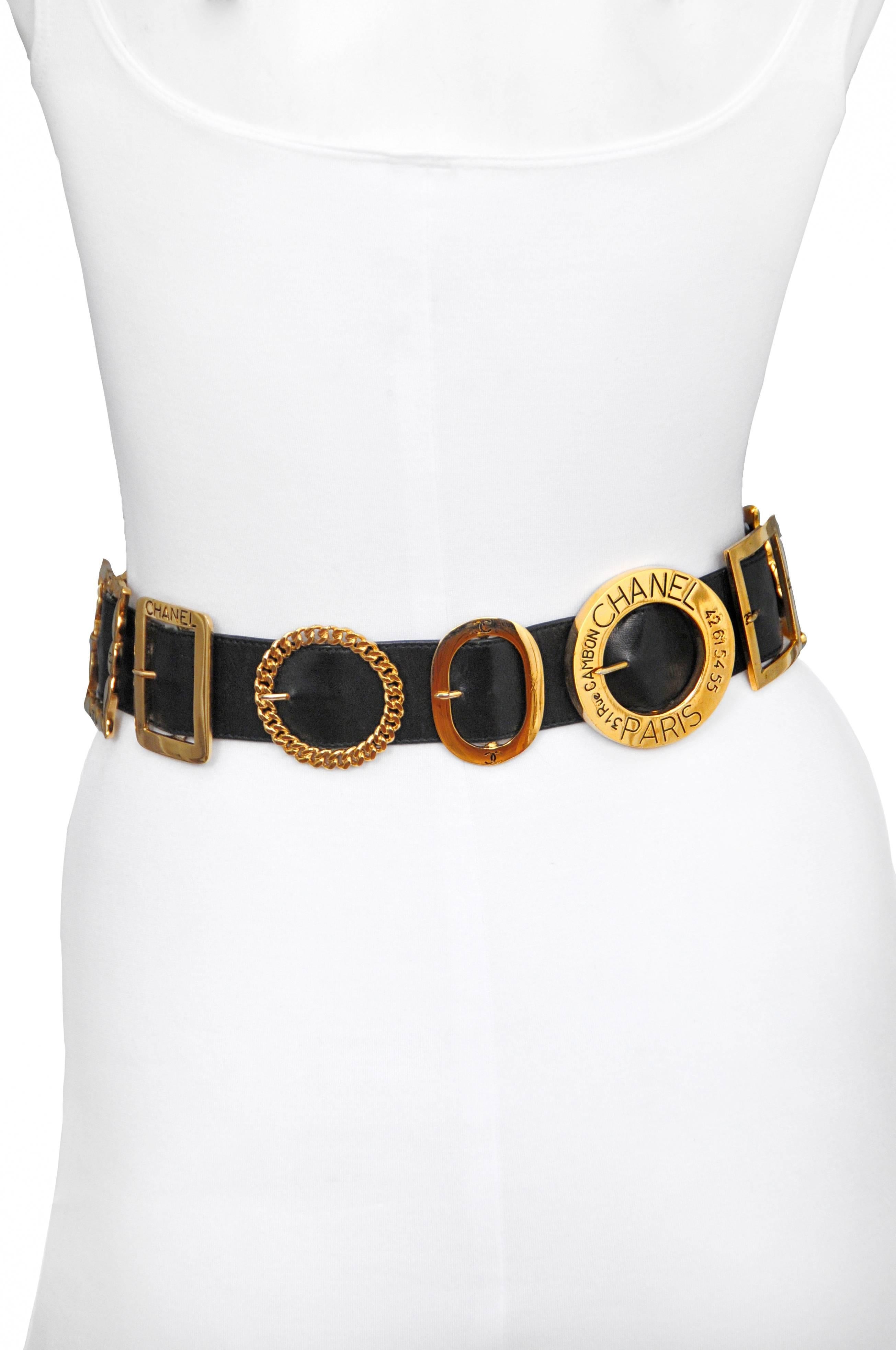 Vintage Chanel black leather belt featuring various styles of gold tone buckles throughout. 