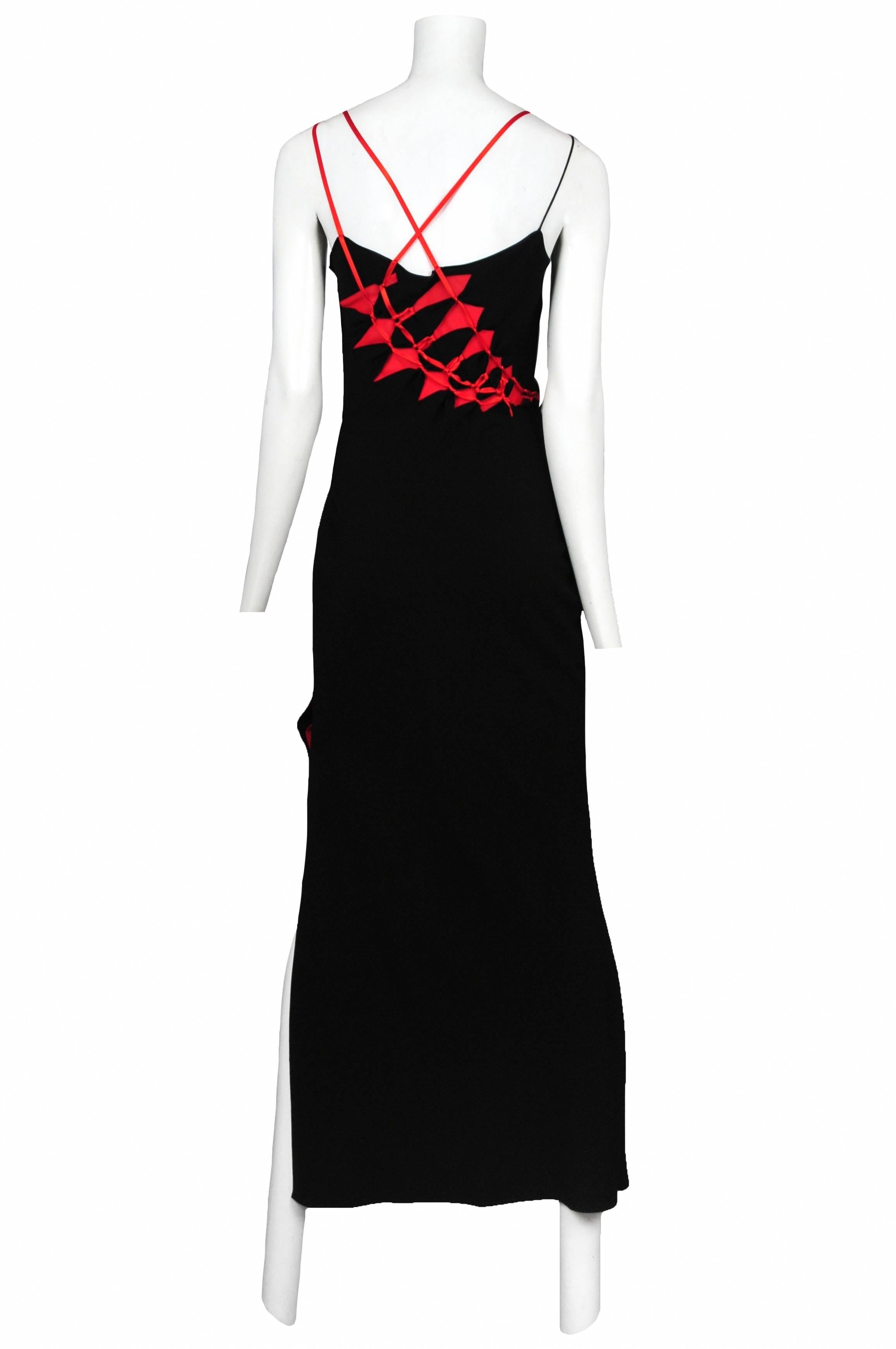 Vintage John Galliano black jersey bias slip gown featuring red ribbon straps and red cutouts that reach from the back and travel along the right side of the dress towards the front hip and are held together with tied red ribbon.