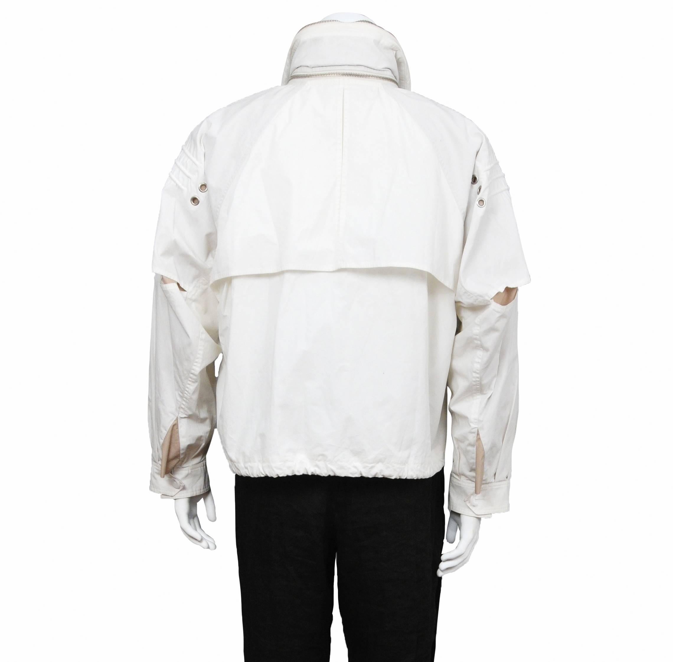 Un raro e da collezione mini bomber paracadute bianco di Raf Simons della collezione SS 2006 dello stilista. La giacca è dotata di cappuccio nascosto, tasche e occhielli e coulisse in vita. 

Presentata in passerella, la giacca presenta numerosi