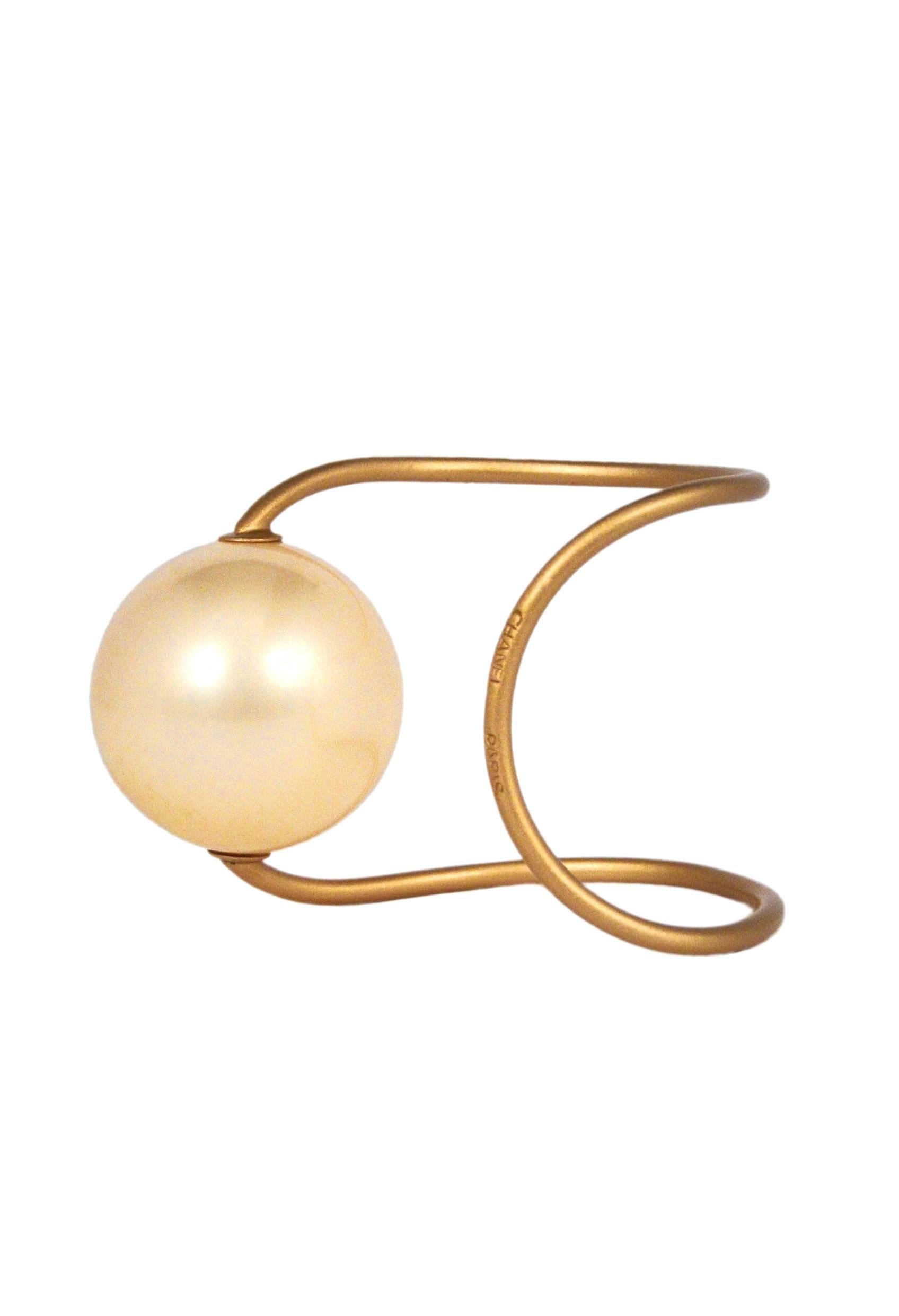 Chanel brushed gold curved wire cuff with oversized pearl bead. 
