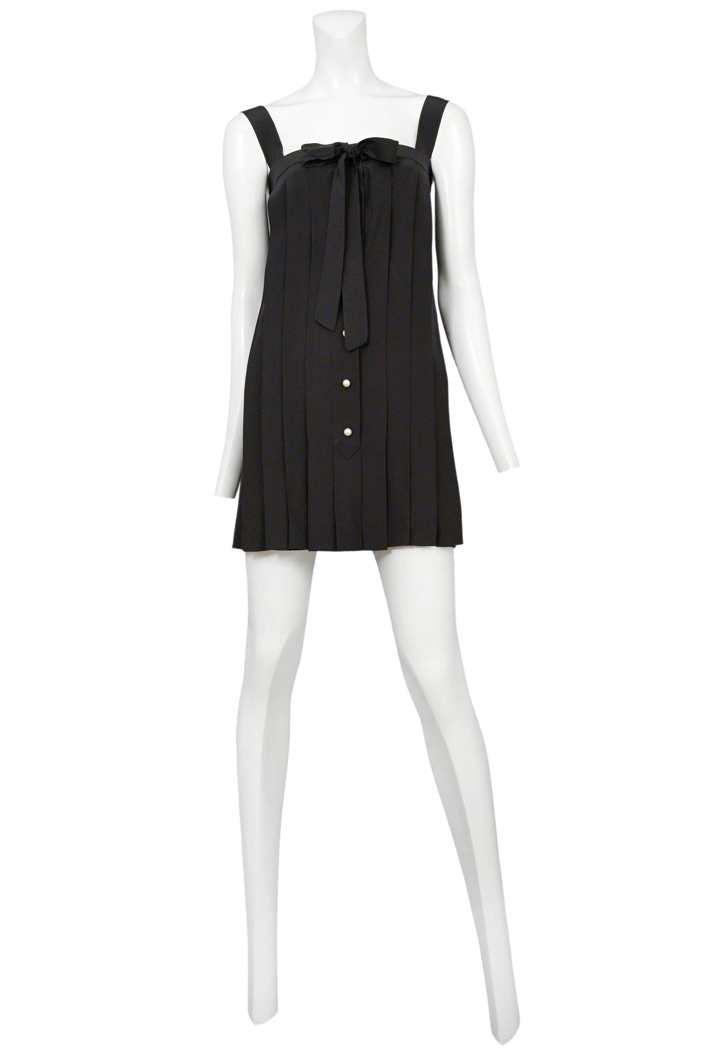 Vintage Chanel black silk mini dress featuring knife pleating throughout, faux pearl buttons along the center front button placket and a ribbon bow at the top of the dress.
Please inquire for additional images.