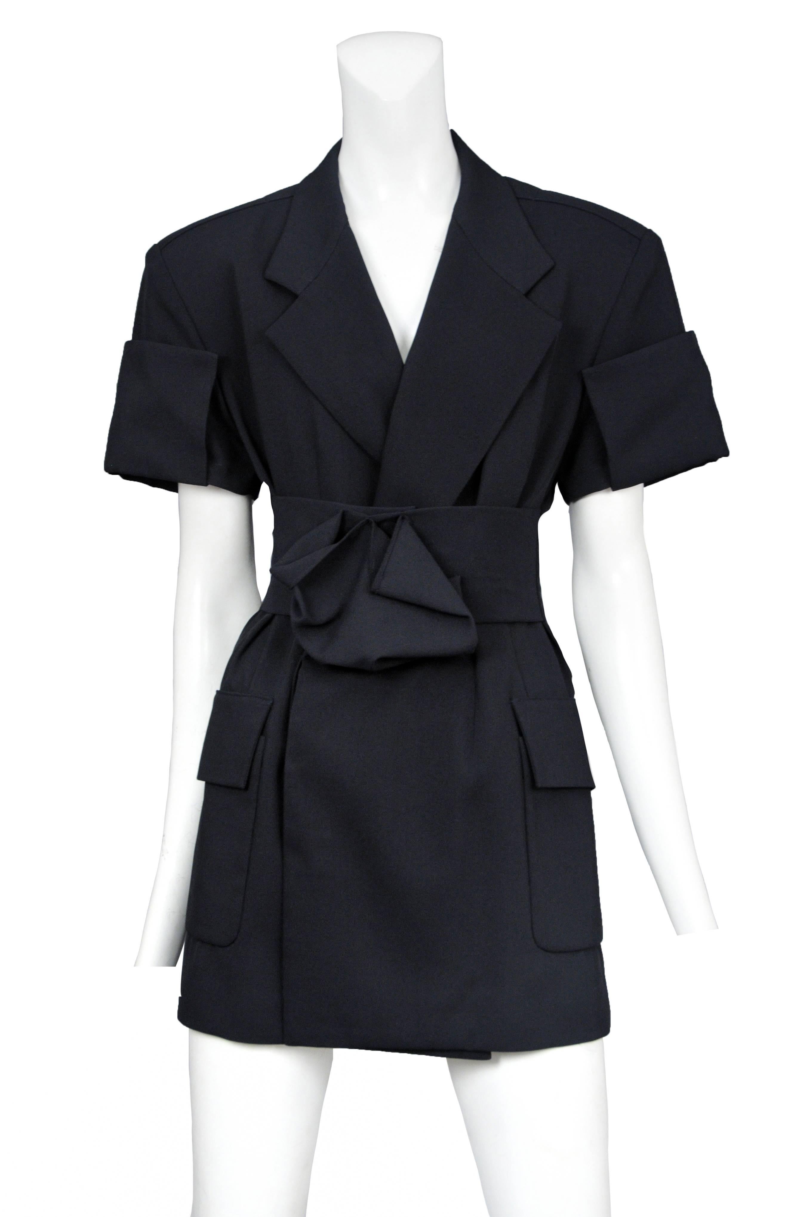 Vintage Yohji Yamamoto navy short sleeve overlapping blazer tunic featuring a wide lapel, side pockets, matching waist belt at front, and origami style pleating at the cuffs and belt center.
Please inquire for additional images.