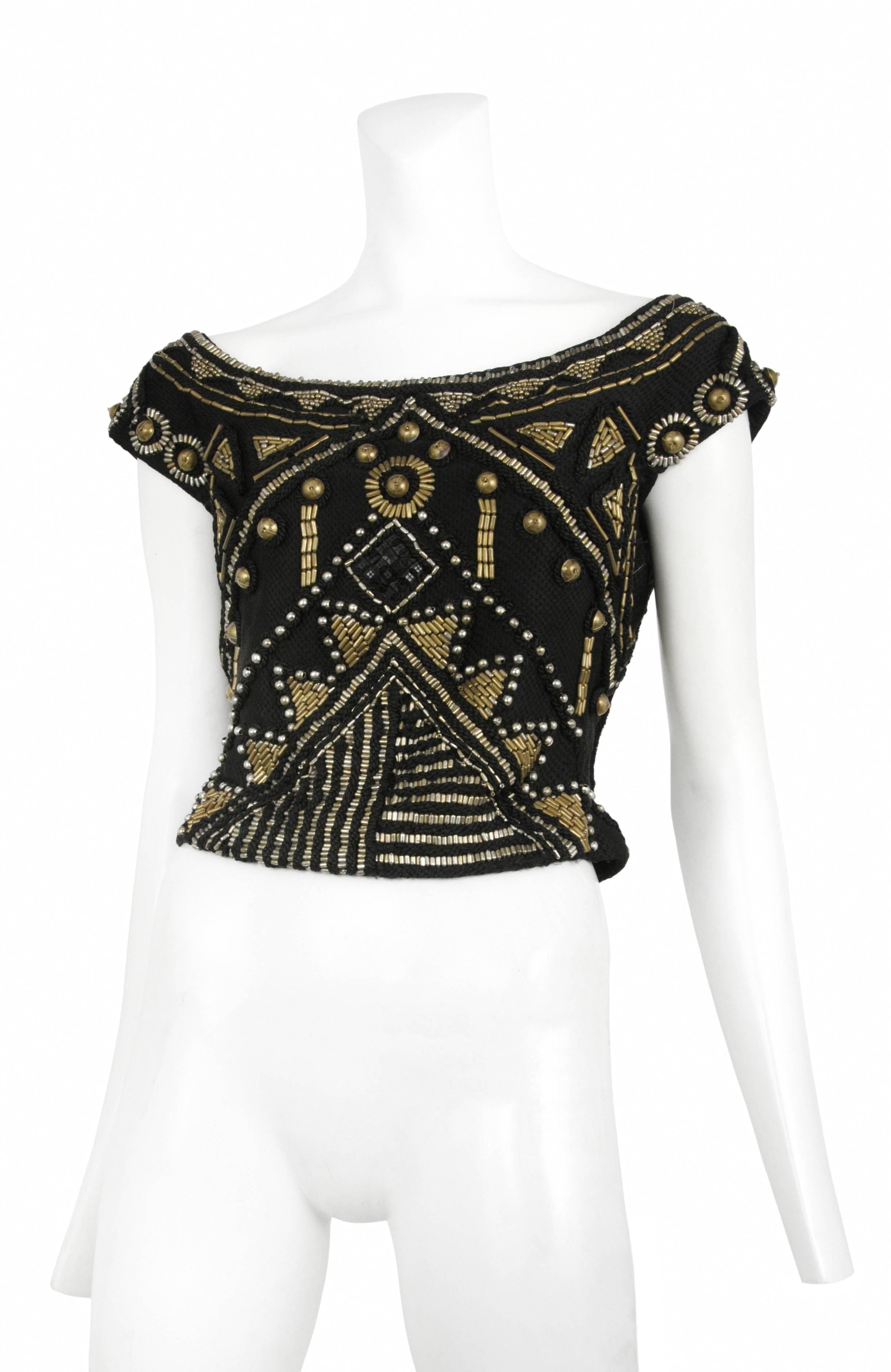 Vintage Gianni Versace heavily encrusted brass colored bead & tact top that falls off the shoulder into a cap sleeve and side zip closure.
Please inquire for additional images.