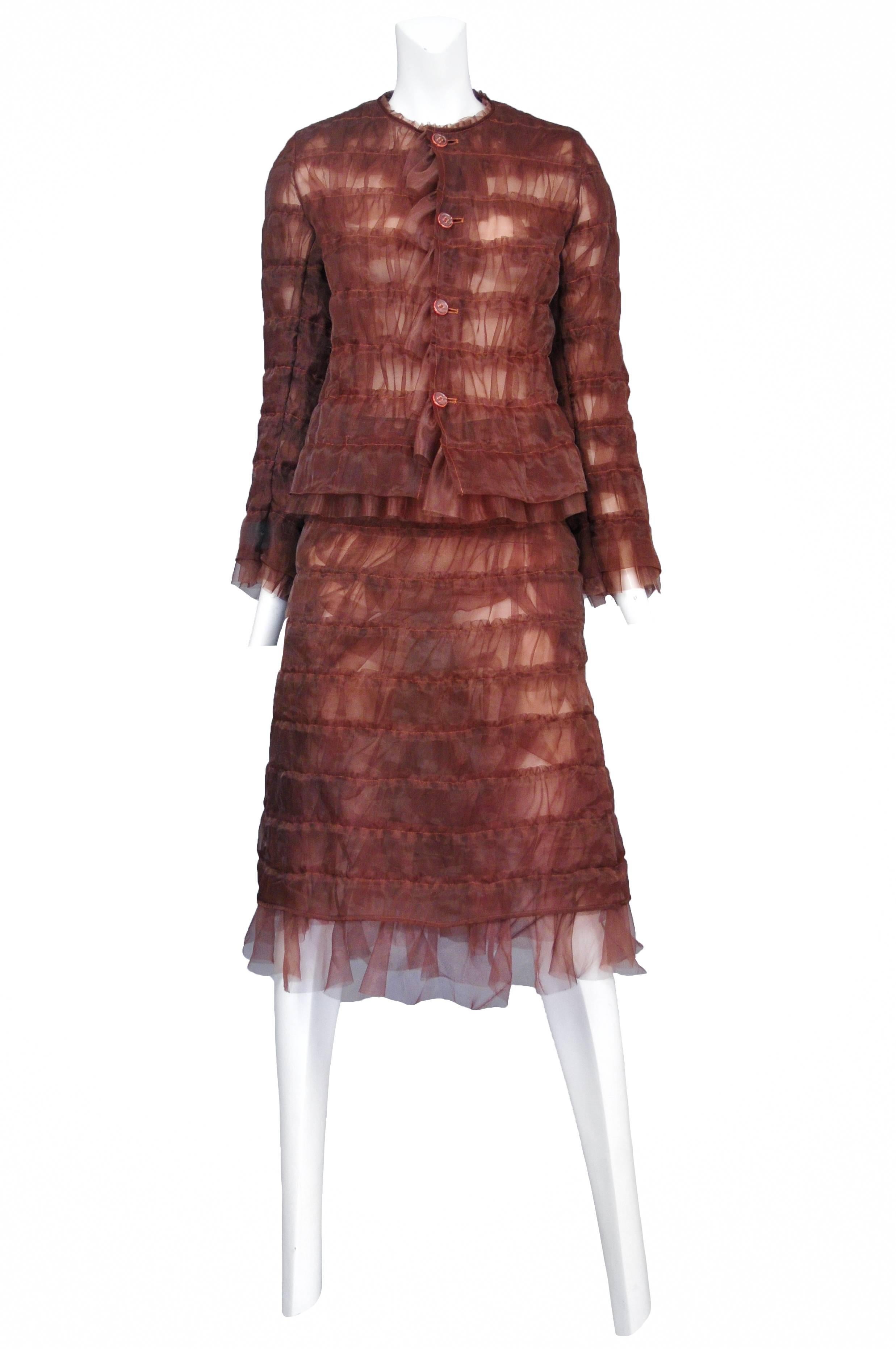 Vintage Junya Watanabe copper nylon suit featuring a four button front blazer with inverted stitched horizontal rows and ruffles at the hem and cuffs. The suit comes with a matching copper knee length skirt featuring the same horizontal stitching