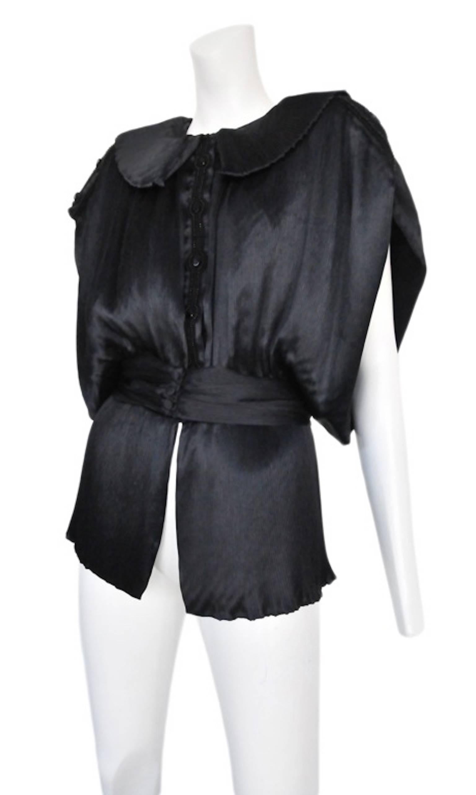 Black satin button down kimono inspired blouse with large round-cornered collar, waistband, and subtle pleated detail. Circa 1987.
Please inquire for additional images.