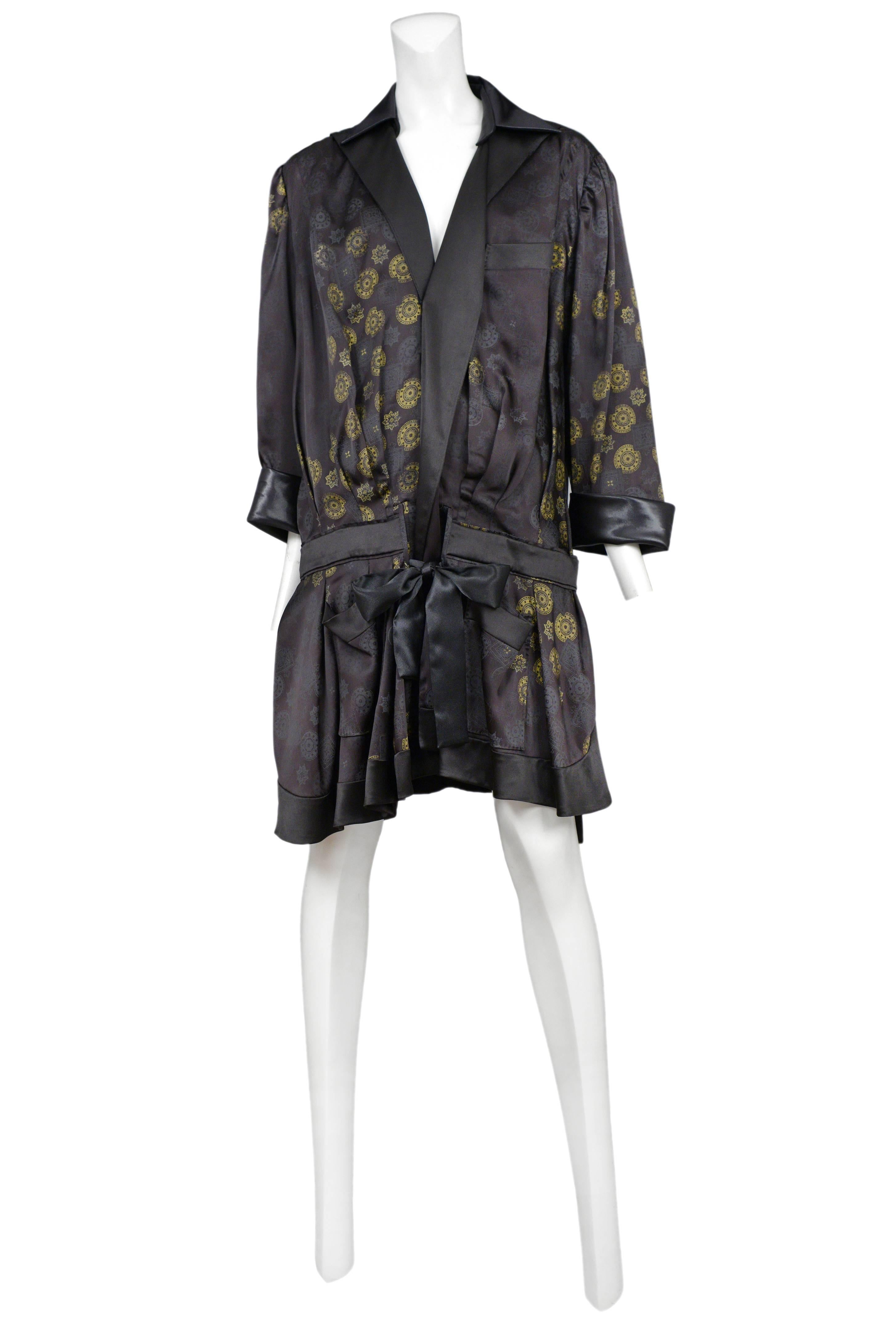 Vintage Nicolas Ghesquière for Balenciaga black satin smoking robe long sleeve dress featuring a built in dropped waist belt, a gathered skirt, a chest pocket and an allover black and gold abstract gear print. Runway piece from the Spring / Summer
