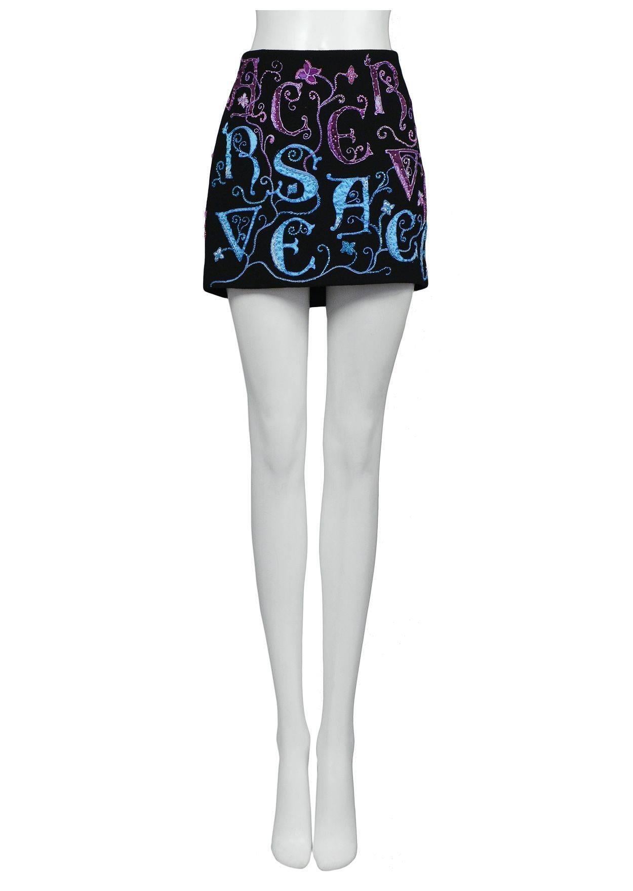 Vintage Versace atelier black mini skirt with blue, purple, and coral embroidered Versace lettering and floral details at front and back.

Excellent Vintage Condition.