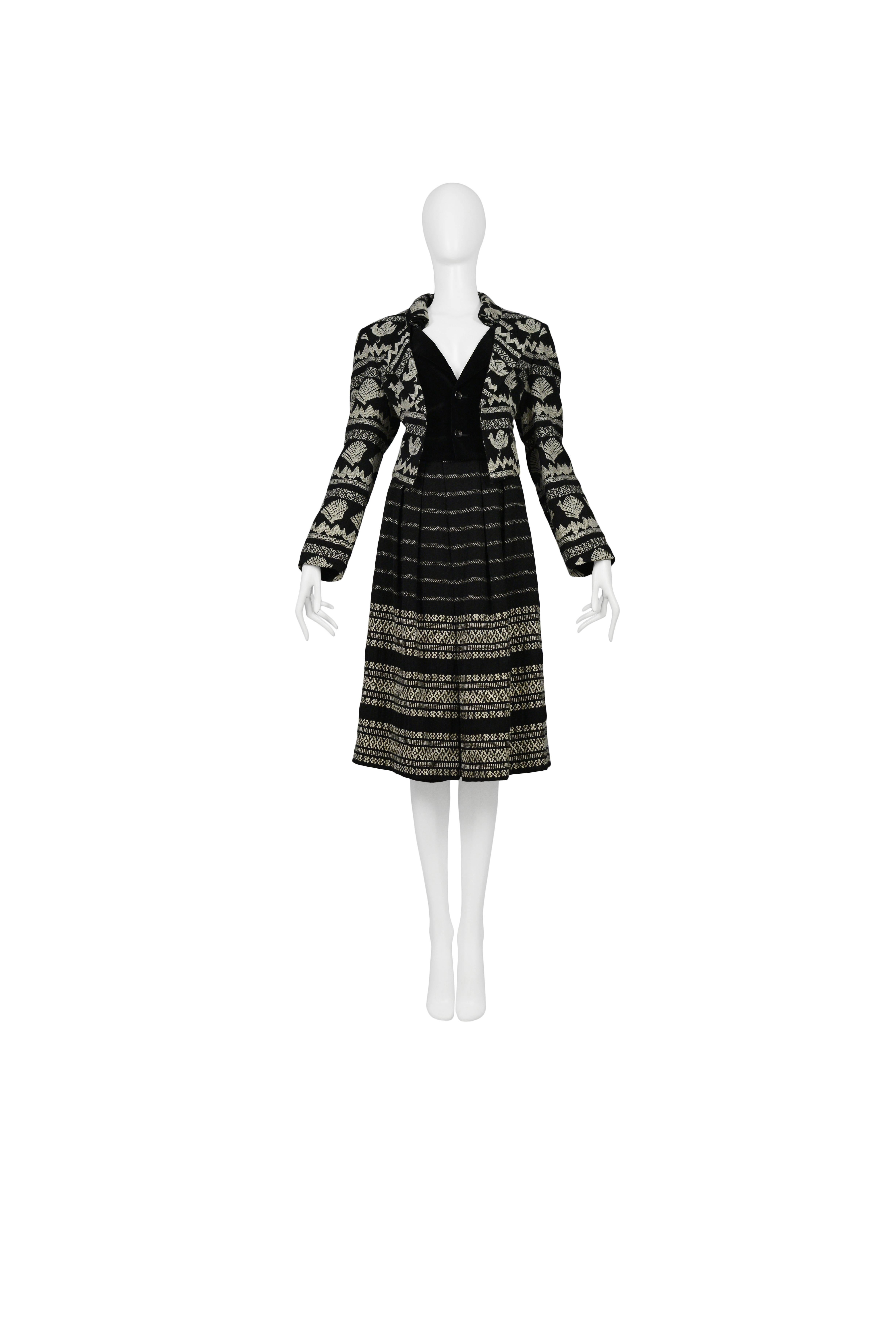 Vintage Comme des Garcons black and white embroidered ensemble featuring a two button front black wool jacket with a black velvet interior panel and white ethnic embroidery throughout. The ensemble includes a black wool knee length skirt with white