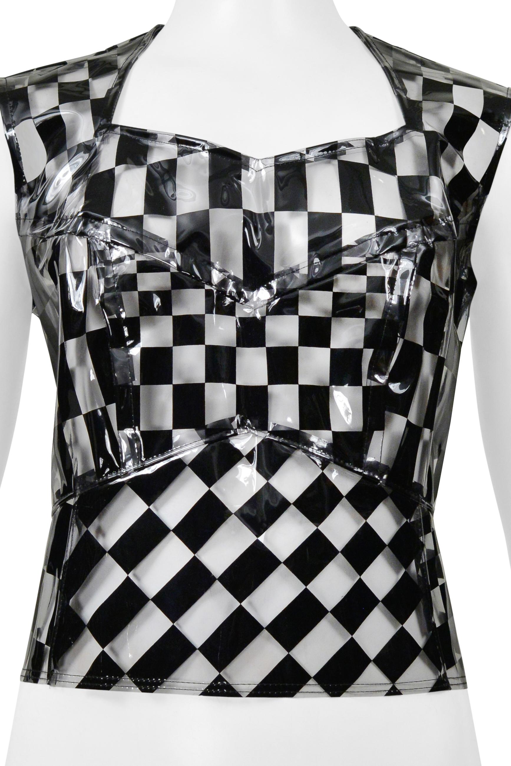 Resurrection Vintage se complace en ofrecer un top corsé vintage Comme des Garçons de vinilo transparente y estampado de cuadros negros de la colección SS 2001, con costuras y detalles de corsé, cuerpo entallado y cremallera central expuesta en la