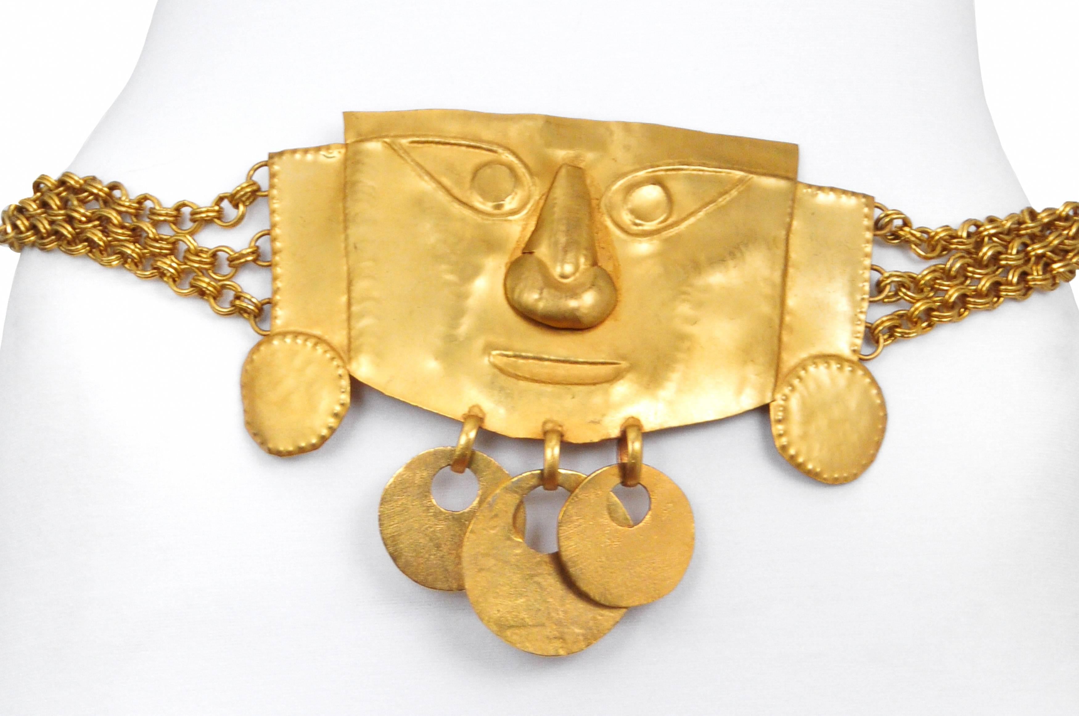 Impressive and unusual vintage Yves Saint Laurent YSL belt made of gold tone hammered metal mirroring traditional Peruvian funerary masks that has three discs hanging from the bottom and is suspended from three gold chains that close with an S hook