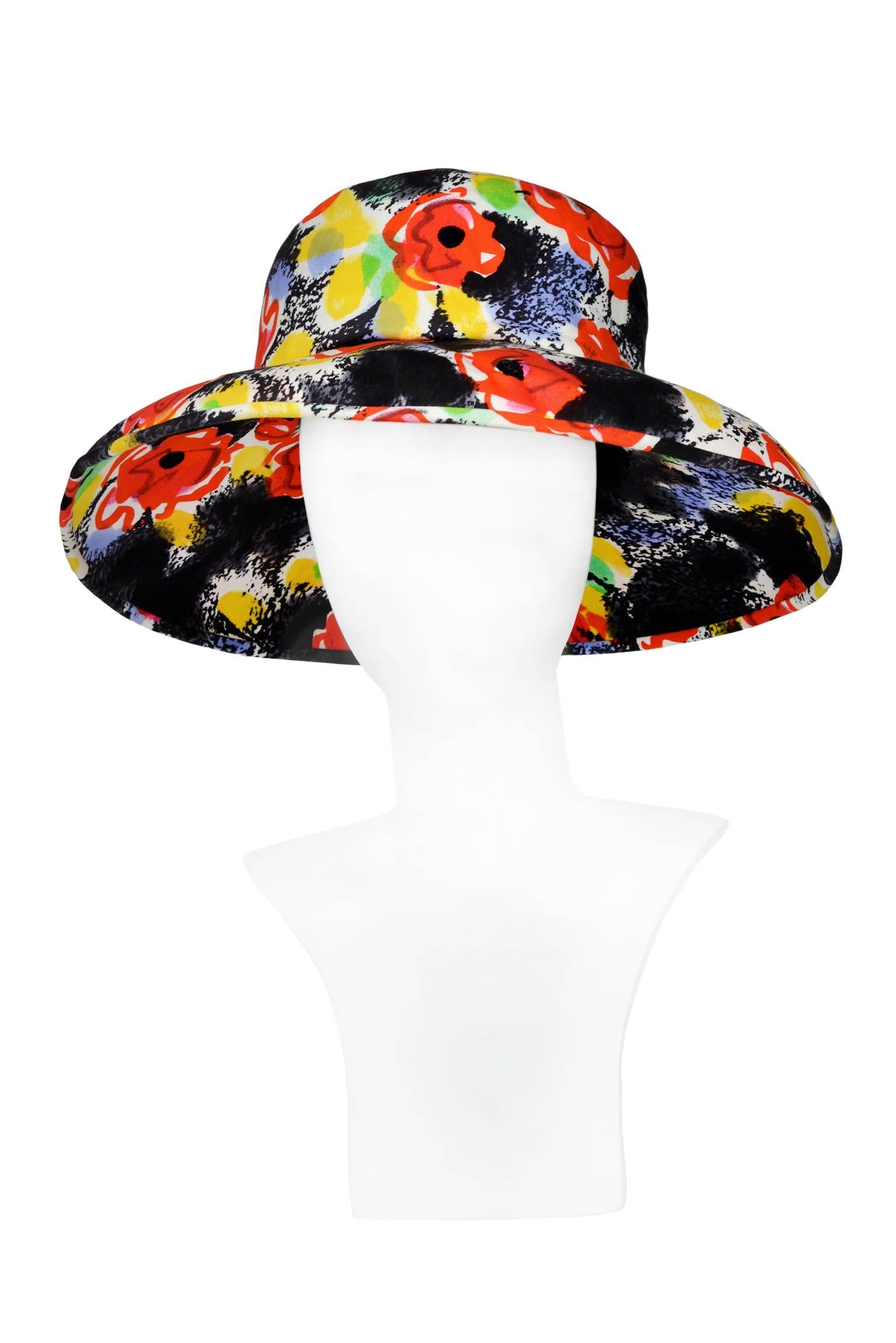 Vintage Chanel black cotton sun hat with red and yellow floral "Camellia" Pop Art style print. Large rim with small rim at back to easily lounge against a chair or chaise. Chanel label inside and interior headband finished with ribbon.