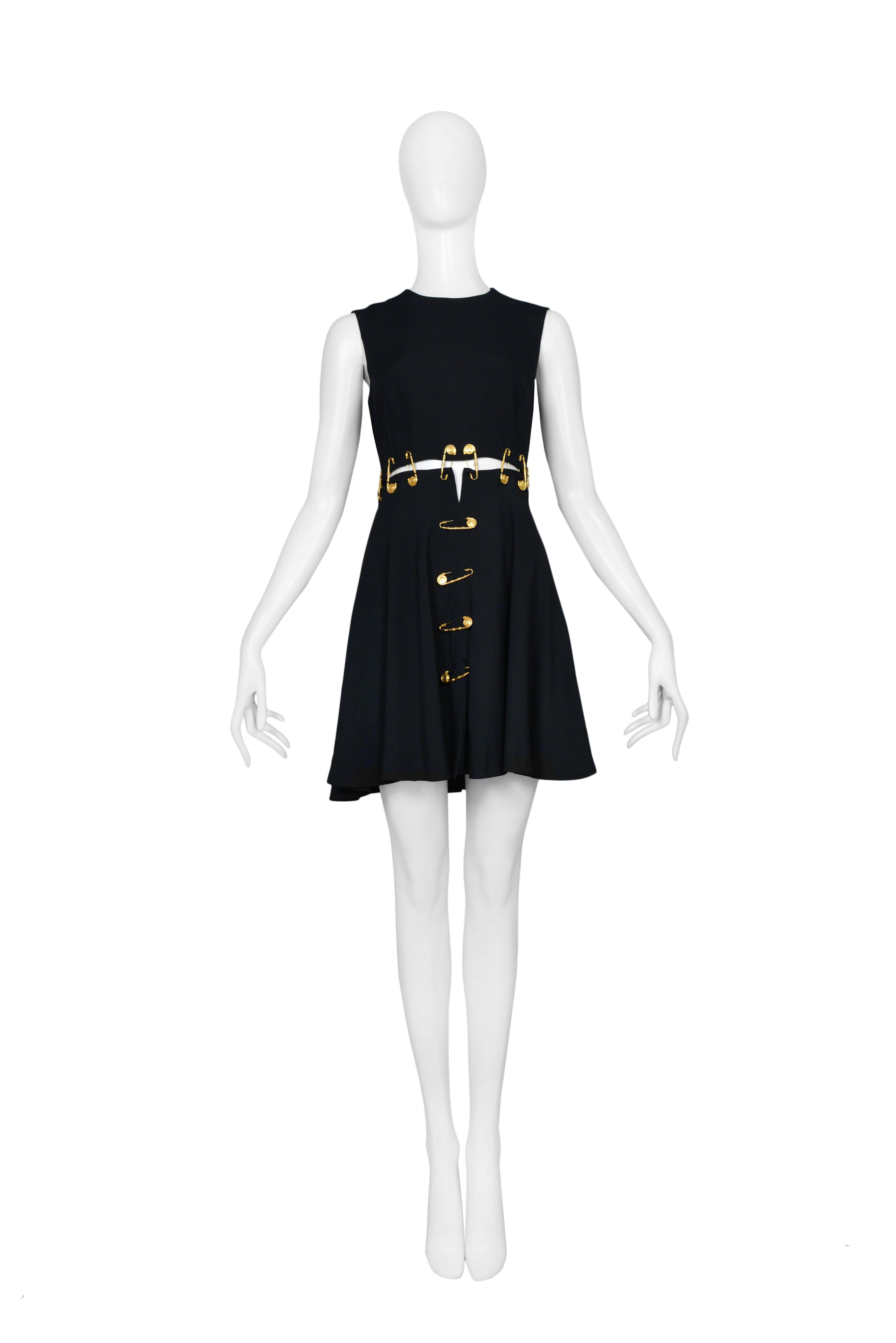 Important and rare vintage Gianni Versace black safety pin mini dress from 1994. The black sleeveless dress has open slits at waist line, center front and center back seams that are closed and decorated by large Versace gold tone safety pins.