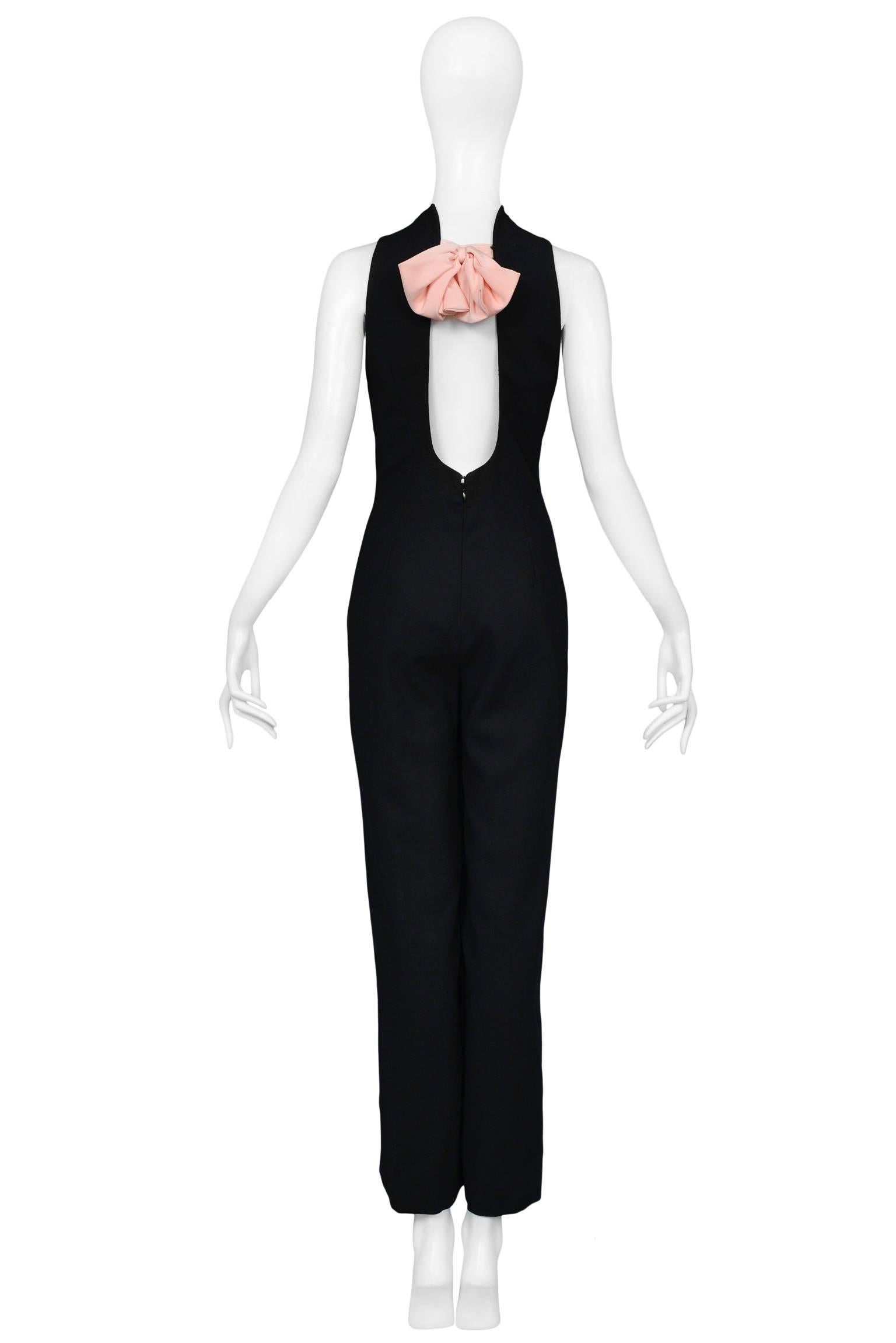 Vintage Gianni Versace designed black evening jumpsuit with an open back and large pink bow. The sleeveless jumpsuit features a tailored torso, scallop neckline, and horizontal tabs across the center front of the bodice. Slim and easy trouser