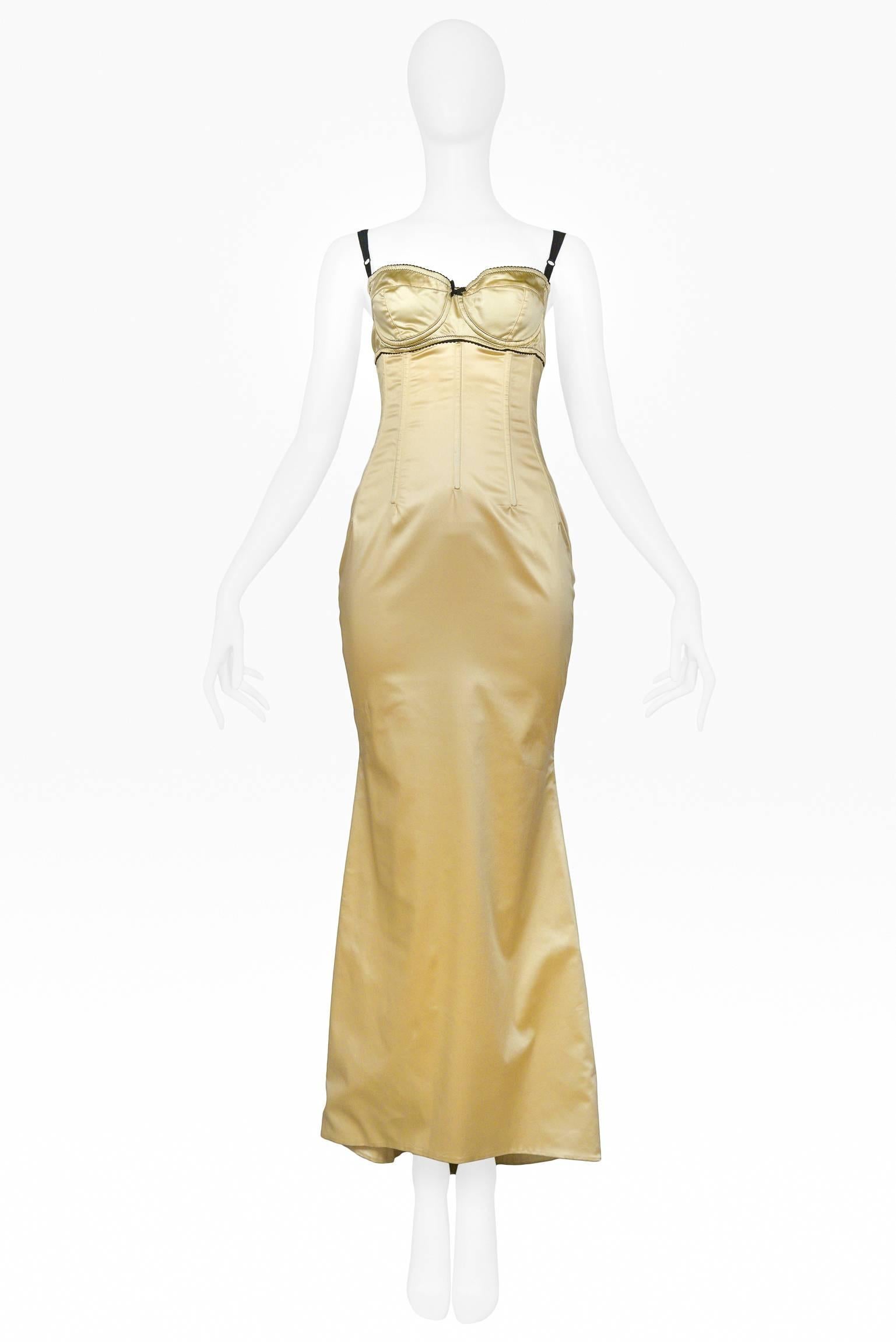 Dolce & Gabbana pale yellow satin evening gown with detailed bra detail, black straps, black satin bow, and black lace trim. The dress features a fitted and seamed bodice, and the skirt of the dress features a train back. Hook and eye closure at bra