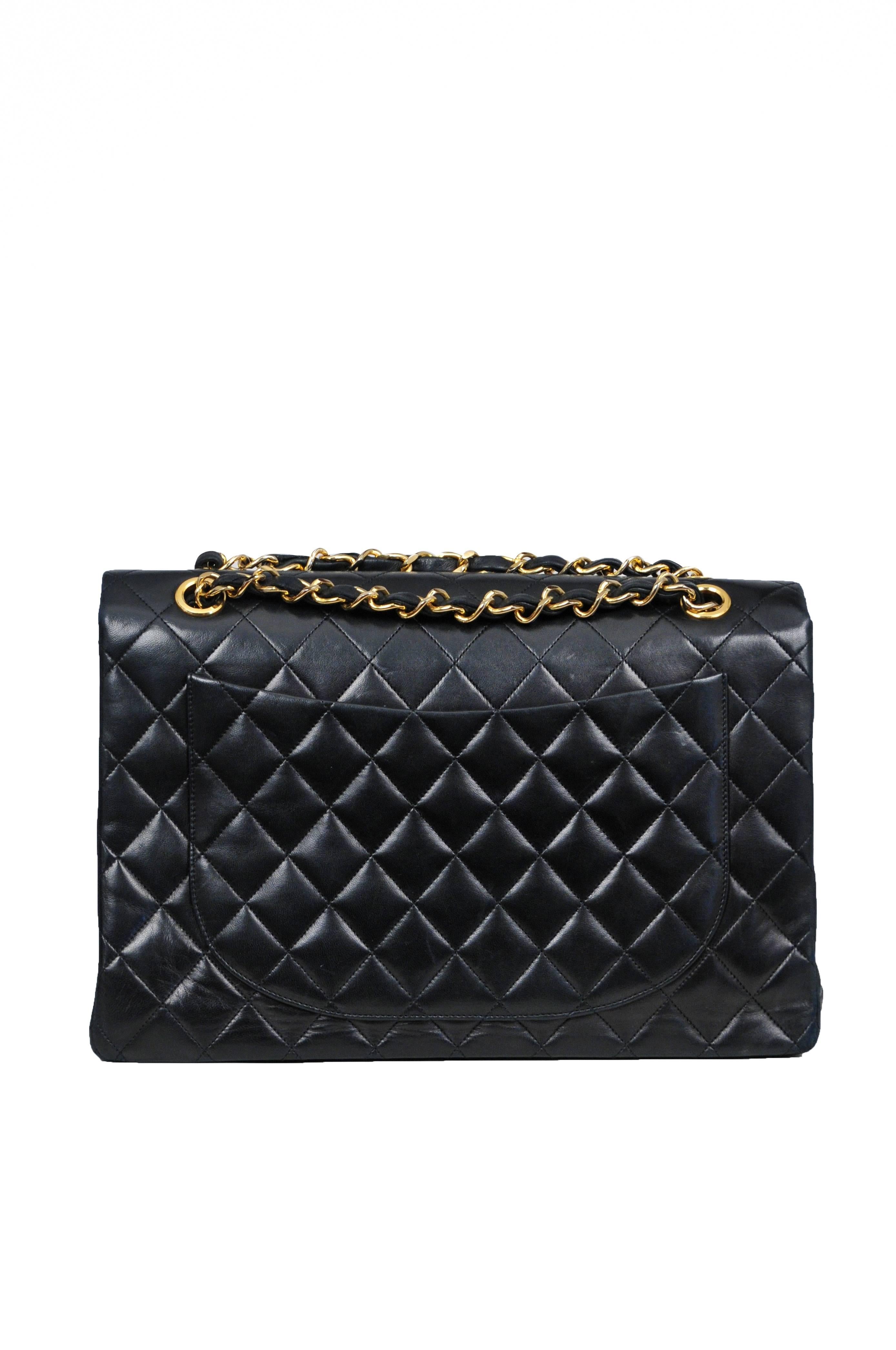 Vintage Chanel Classic XL jumbo single flap bag in black quilted lambskin featuring leather interior lining, iconic leather and gold tone chain woven straps, a classic patch pocket at the back, and a gold tone turn-lock closure at the front. The bag