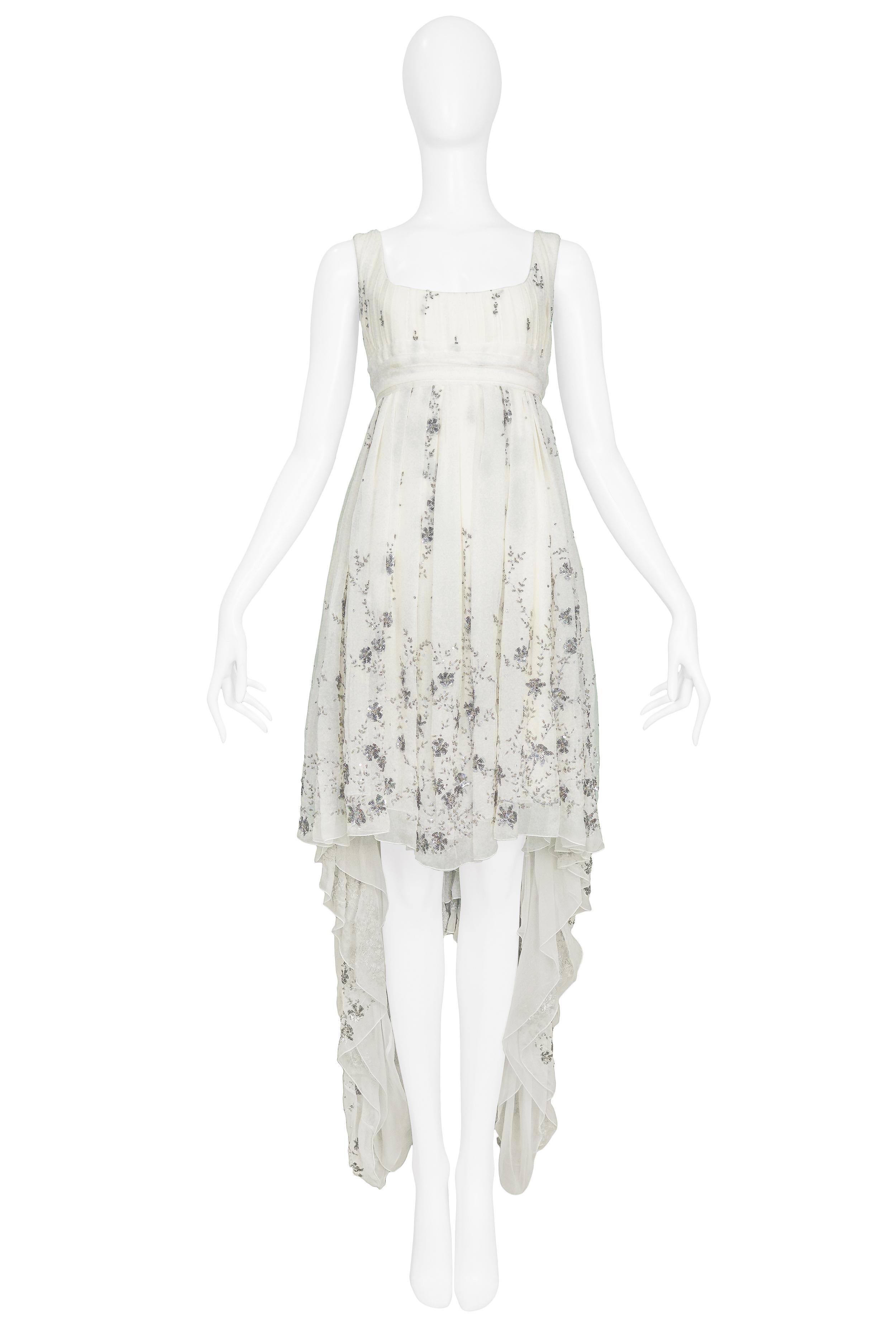 Vintage Alexander McQueen ivory chiffon empire gown with silver tone chain, bead & sequin floral embelishments. The gown features an asymmetrical hankerchief hem and a built in sash that ties in the back. Featured on the Autumn/Winter 2003