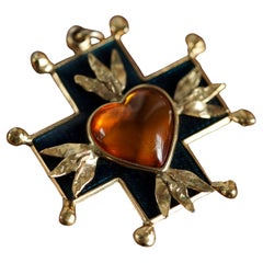Spilla con ciondolo a croce Yves Saint Laurent d'epoca con cuore d'ambra e smalto blu Spilla con ciondolo a croce Yves Saint Laurent d'epoca con cuore d'ambra e smalto blu
