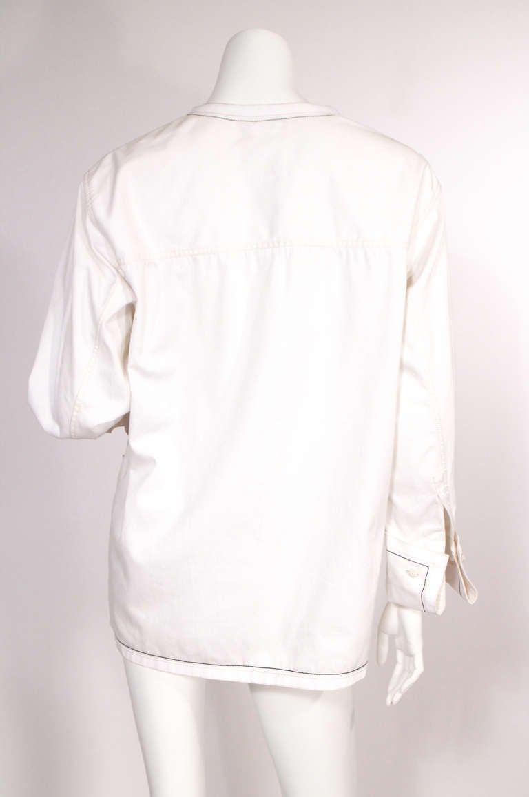 White Chanel "utilitarian" jacket. Simple, chic, and wearable! One CC button at the neckline, lined in black and tan thread, woven cuff links, four pockets. Very good condition.

Size 0-2
Arm length: 23"
