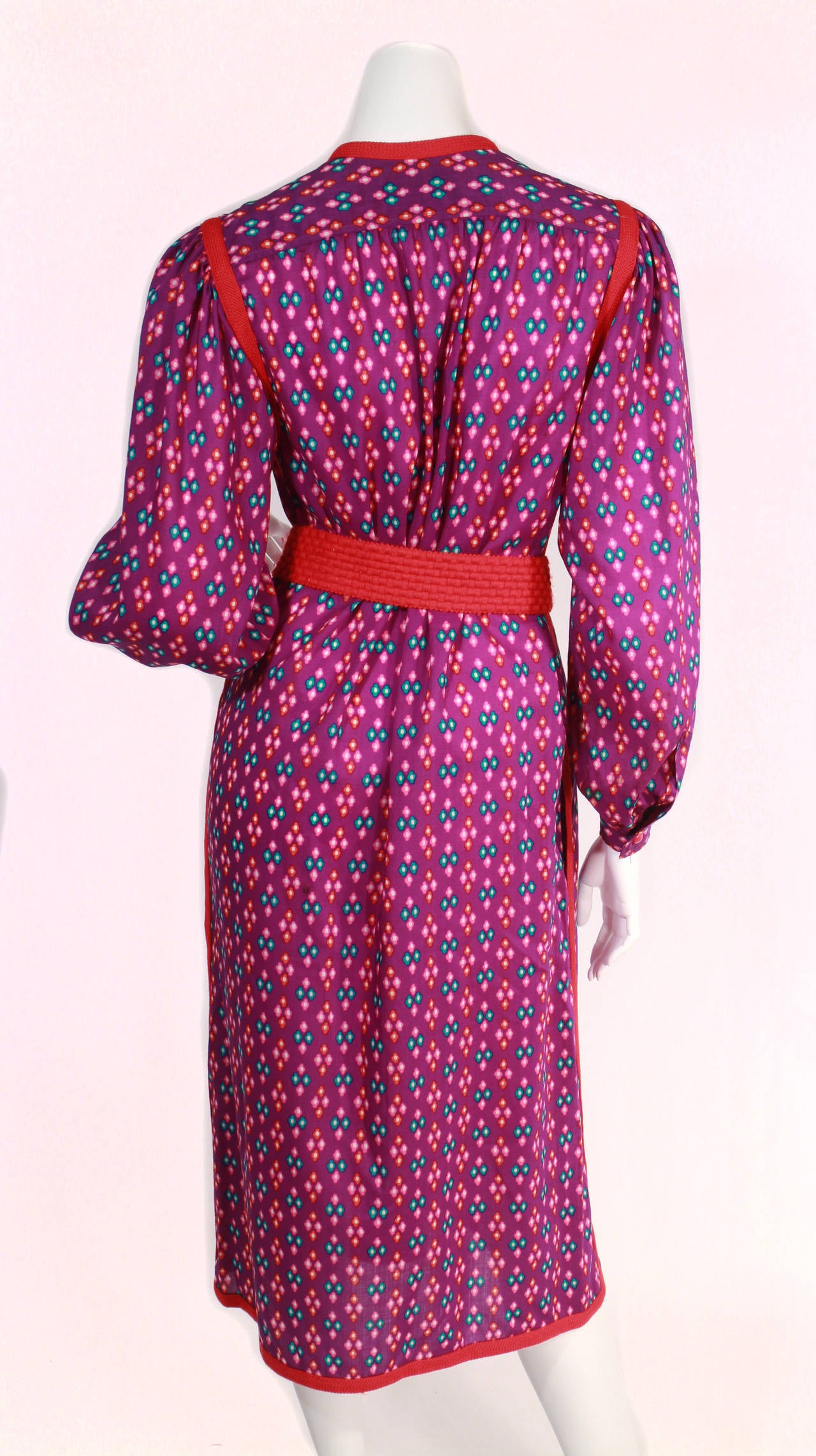 Early Yves Saint Laurent peasant dress. 

Mint condition early YSL peasant/caftan dress featuring a vibrant purple, red and pink print, lined in red wool, has pockets, buttoned cuffs, and neckline.