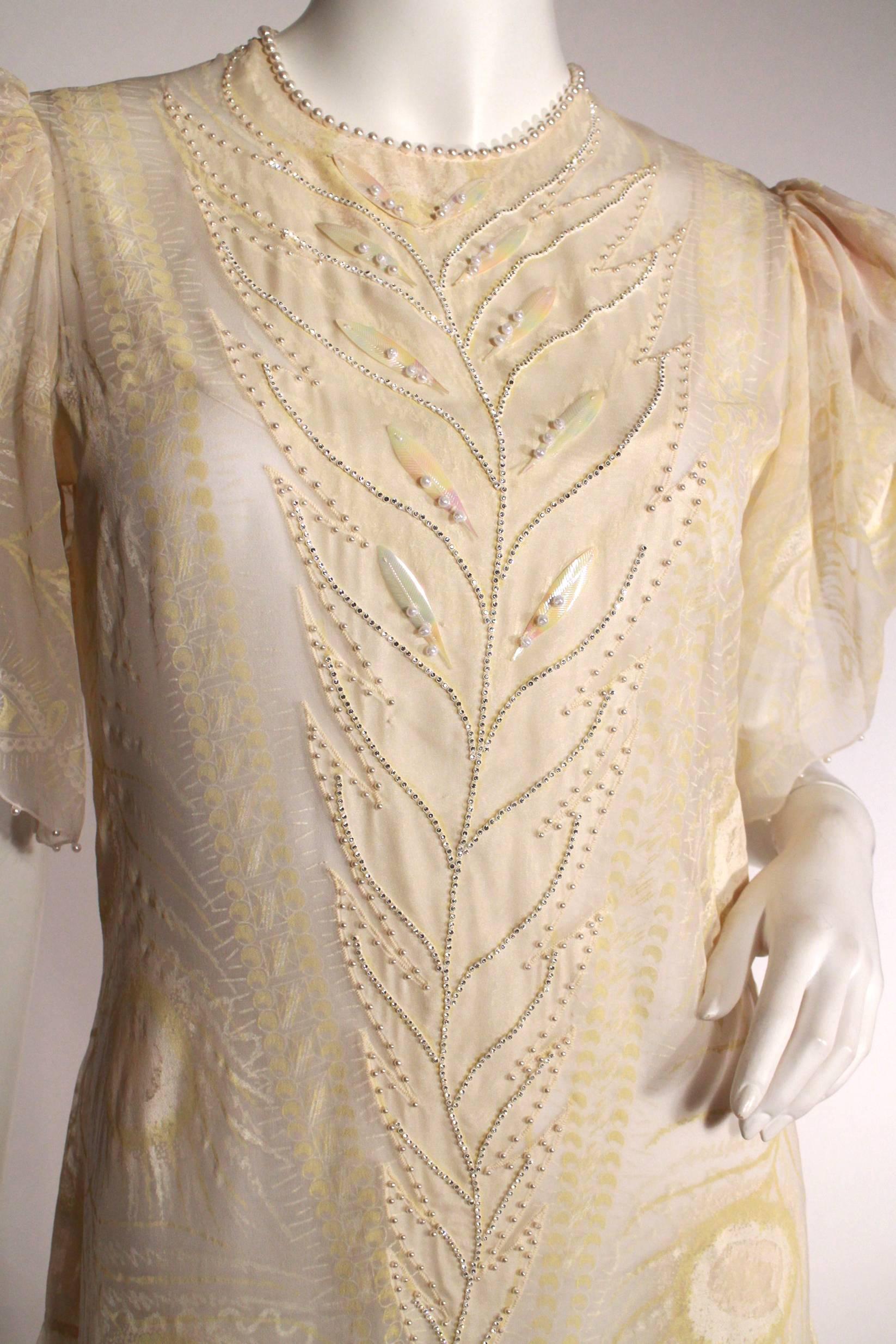 Just try not to strut in this stunning drop waist Zandra Rhodes dress in cream with hand-painted peacock feathers, pearl neckline, iridescent feather applique, petal puffed sleeves and scalloped hems. Excellent Condition.
Measurements:
Length 36