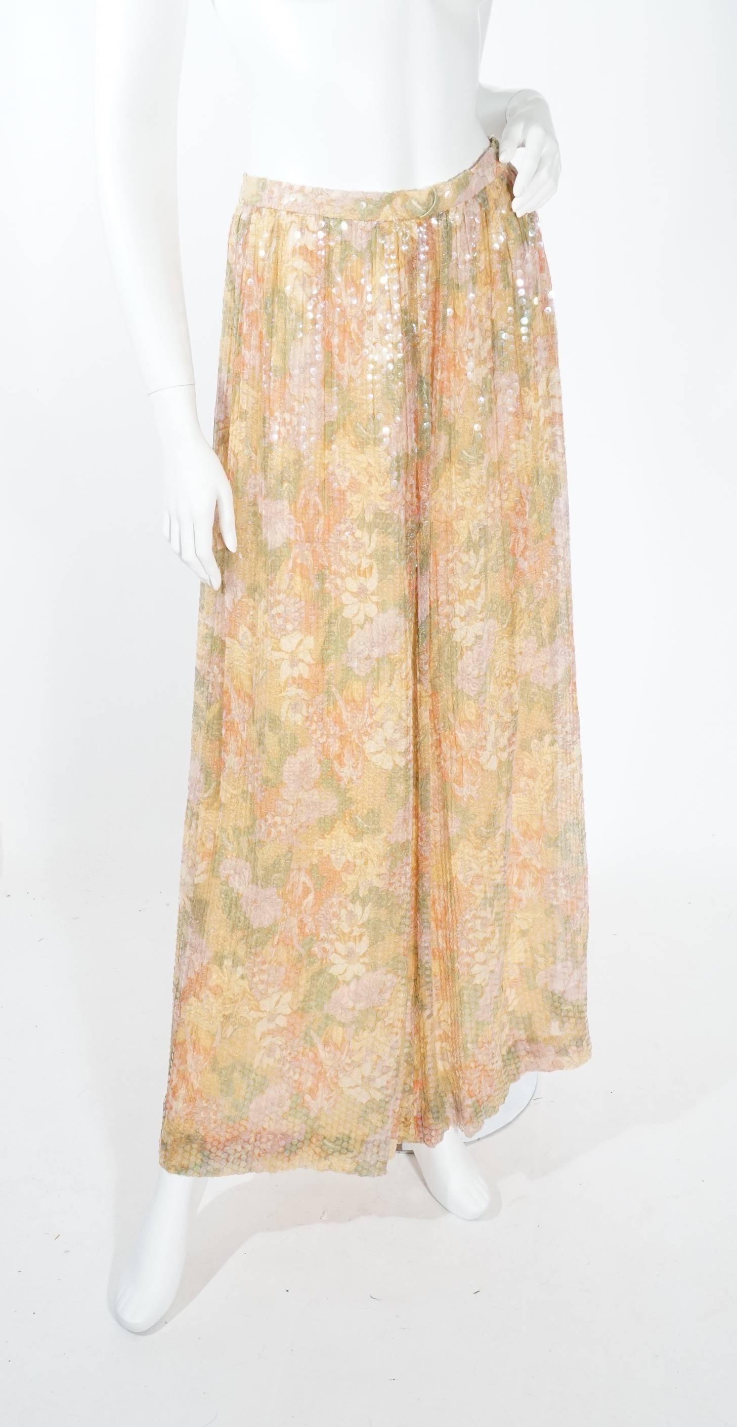 Vintage 1970s Adele Simpson long skirt. This skirt features fully adorned sequins and a gorgeous floral pastel colored print. This skirt is is easily dressed up and down for spring and summer. Fully lined, zip back. Excellent condition.