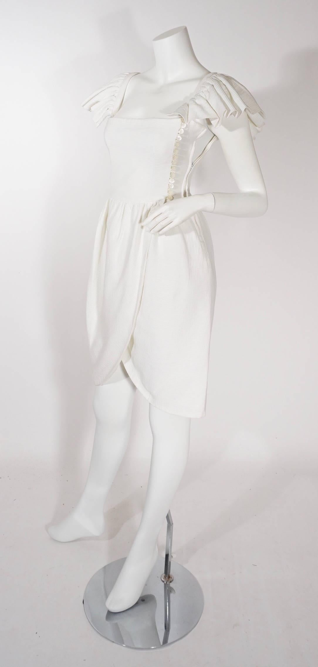 Lanvin white ribbed dress, Circa 1990's. This feminine design features ruffled capped sleeves, buttons along the bust to waist side line, and open skirt hemline. Extremely flattering and timeless. Excellent condition.