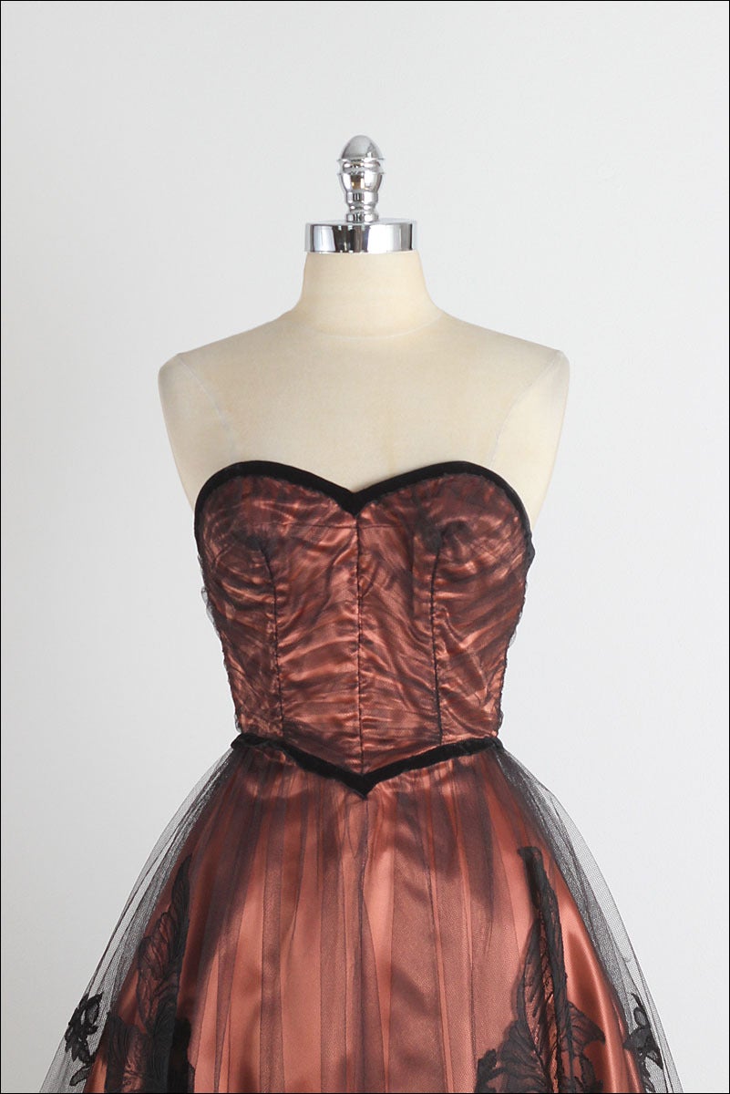 ➳ vintage 1950s dress

* black tulle
* rose copper satin lining
* velvet trim
* boning in bodice
* floral appliques
* metal back zipper
* by Fashion Forecast by Dorothy O'hara

condition | excellent

fits like small

dress length