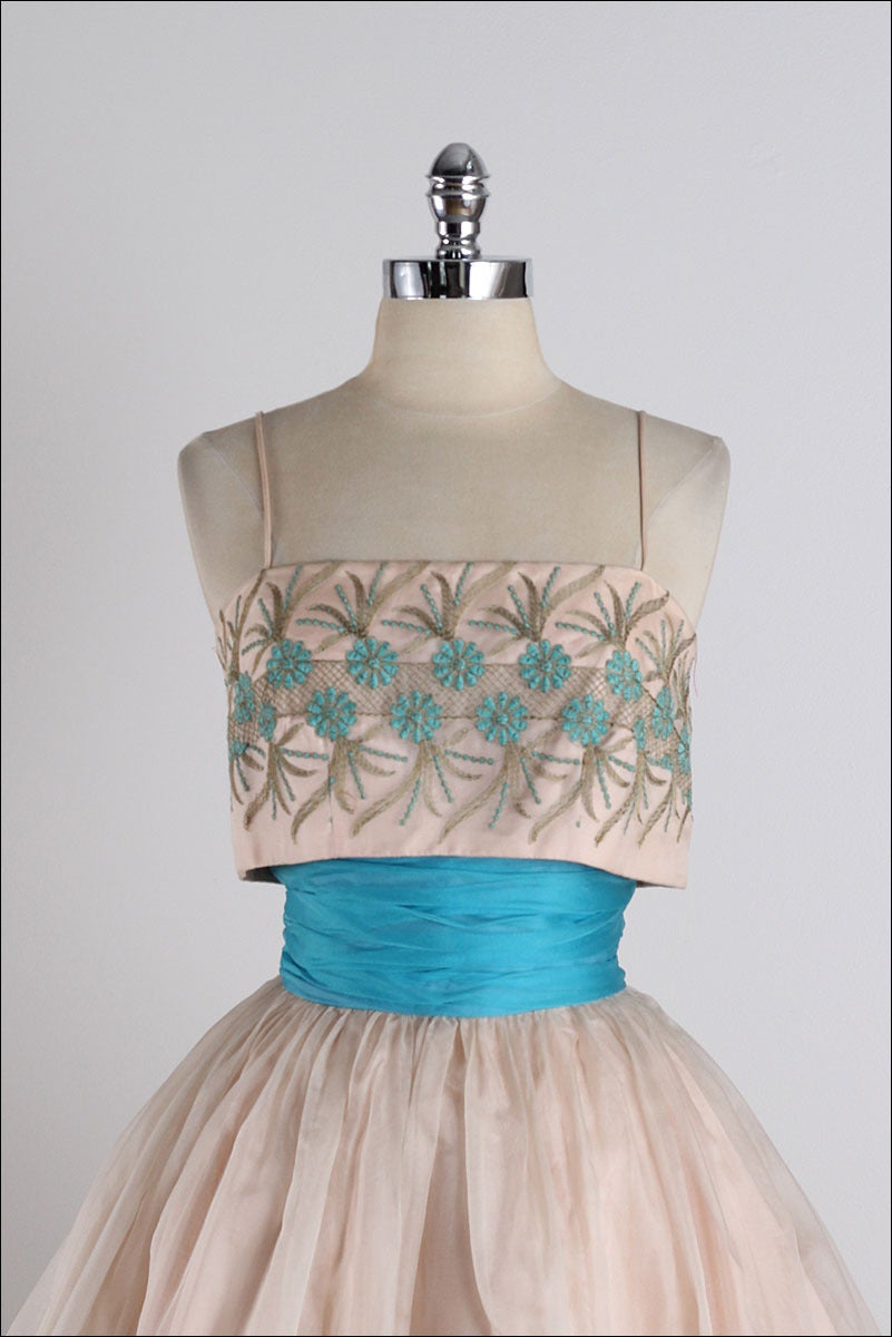 ➳ vintage 1950s dress

* blush organza
* acetate lined bodice
* acetate/tulle lined skirt
* turquoise/gold daisy embroidery
* shirred waist
* metal back zipper
* by Junior Theme NY

condition | excellent

fits like small

length